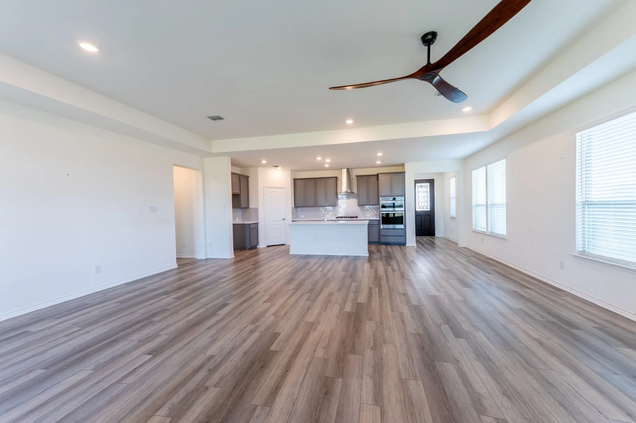 Spacious open-concept layout with wood-finish flooring, a contemporary ceiling fan, and recessed lighting