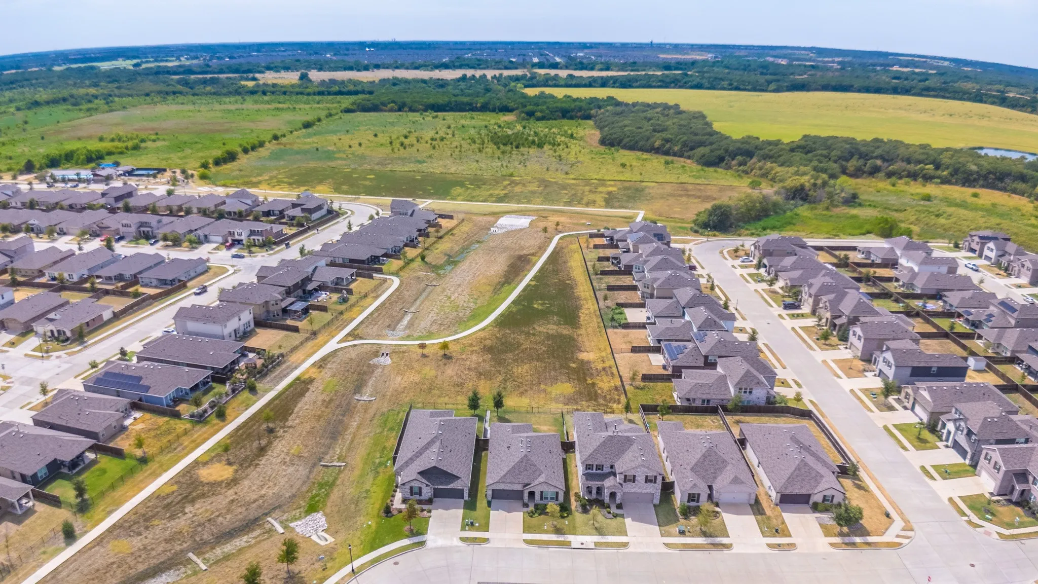 Expansive community featuring numerous single-family residences, paved streets, and a meandering pedestrian pathway