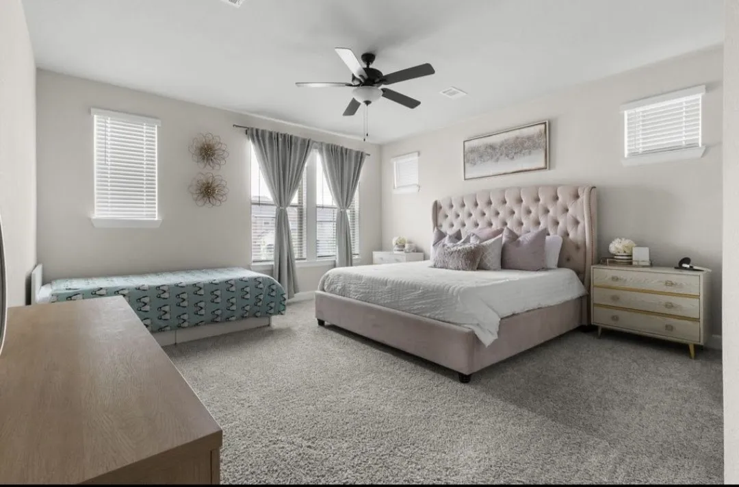 Plush carpeting, multiple windows with blinds, and a ceiling fan