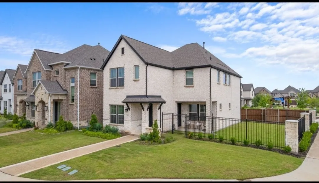 White brick exterior with black trim, covered front entryway, two-story design, fenced backyard, and a covered back patio