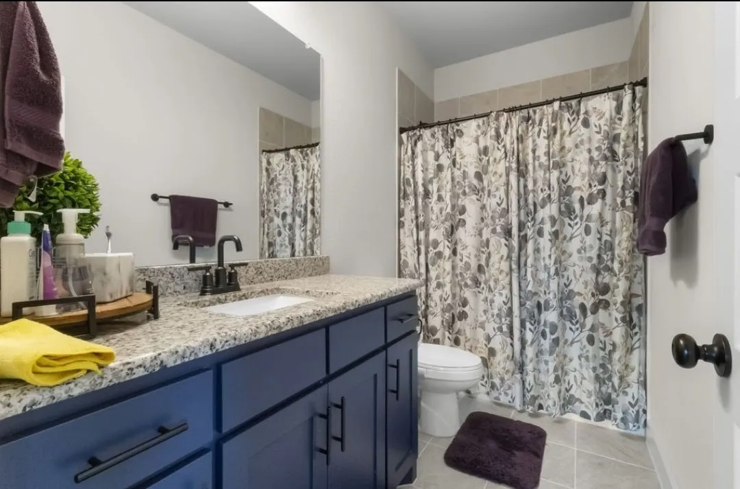 Vanity with a granite-style countertop, undermount sink, and dark blue cabinetry