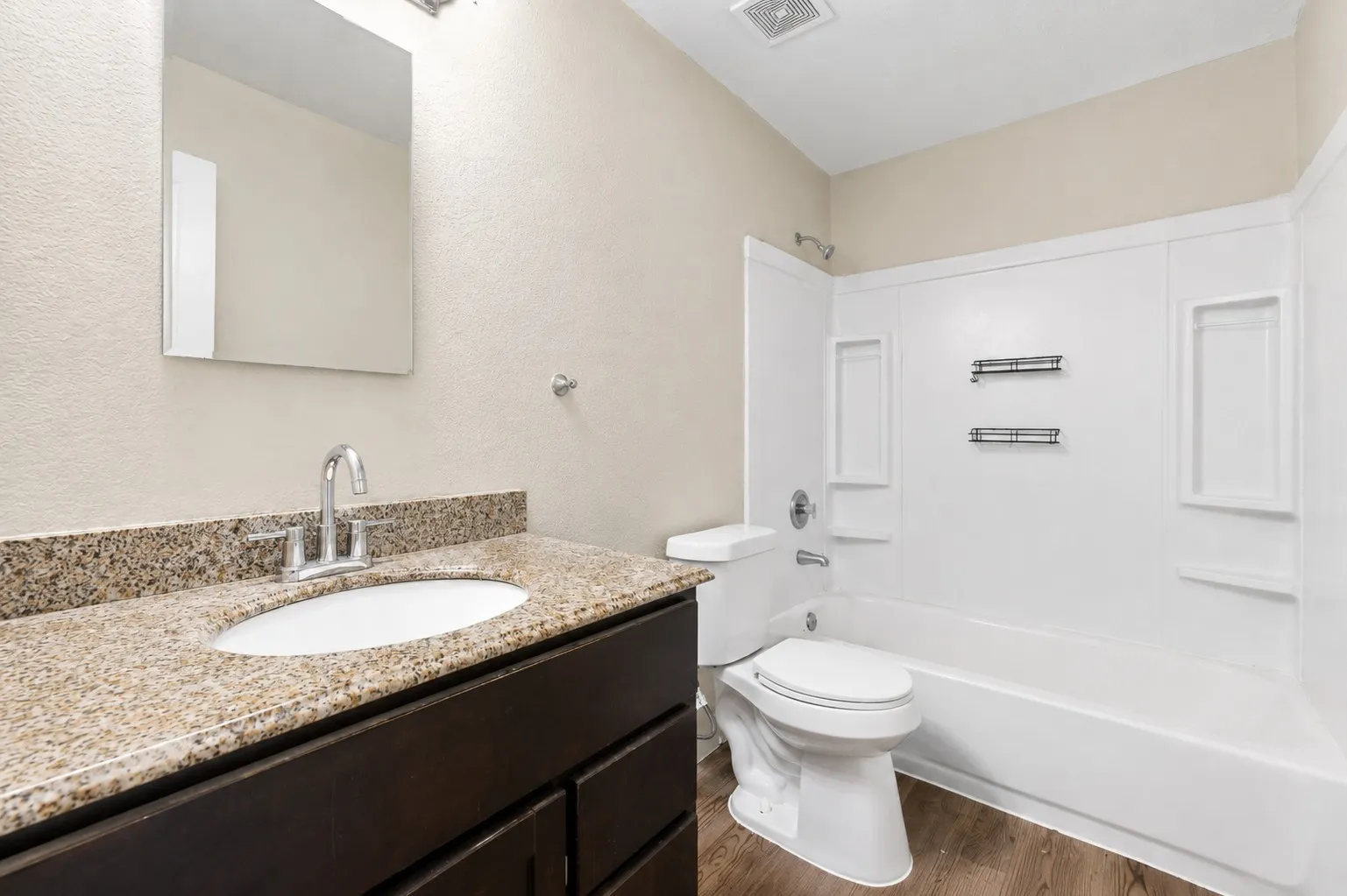 Bathroom featuring a vanity with a granite-style countertop, integrated sink, and chrome faucet