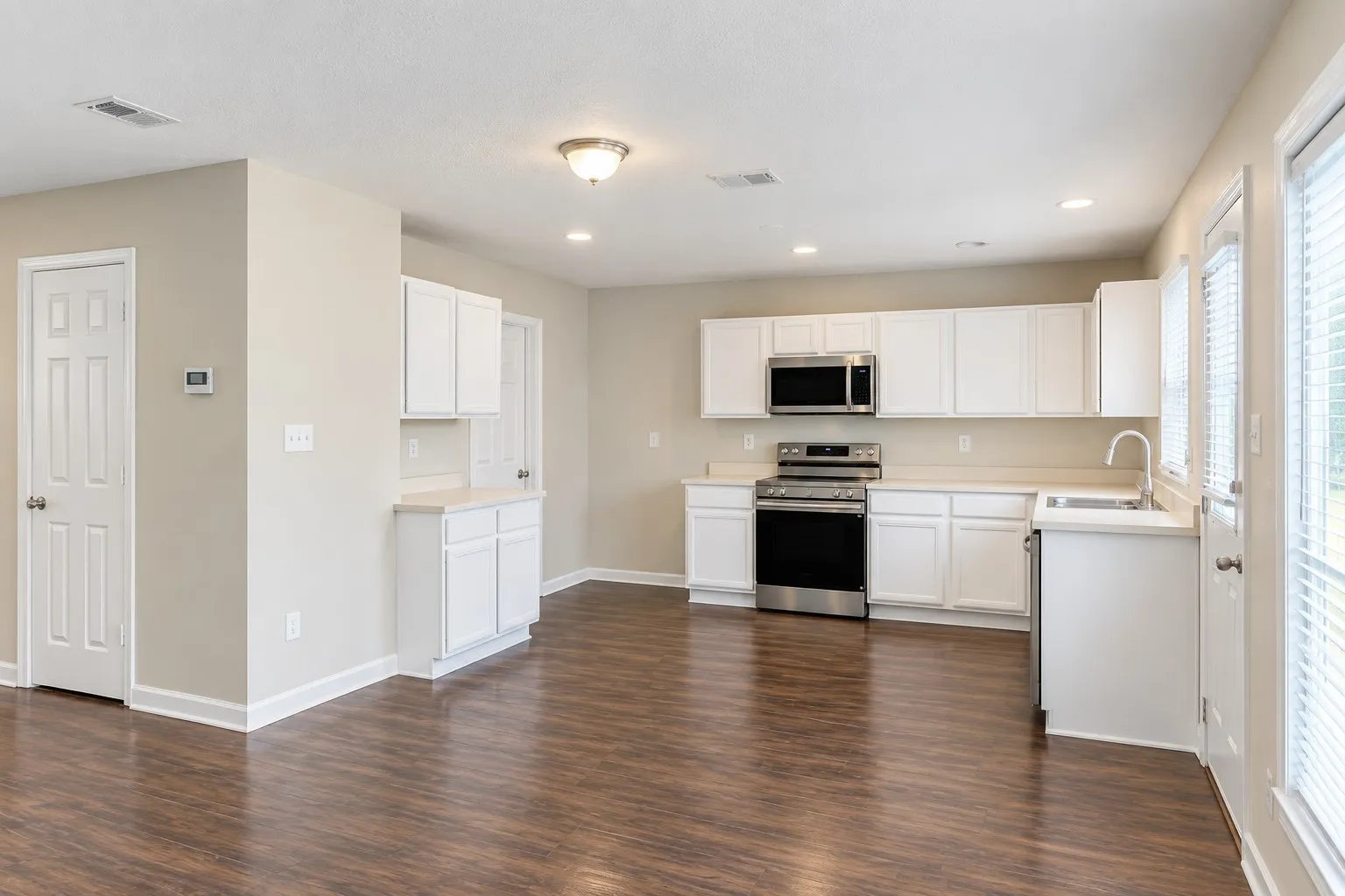 Contemporary kitchen featuring white cabinetry, stainless steel appliances, wood-finish flooring, and recessed lighting