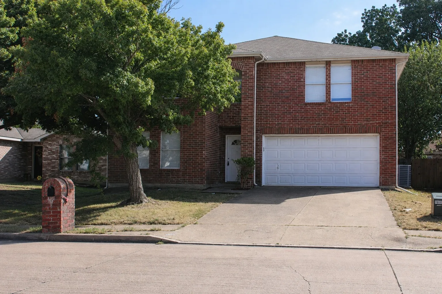 Red brick exterior with white trim, a gabled roof, and an attached two-car garage