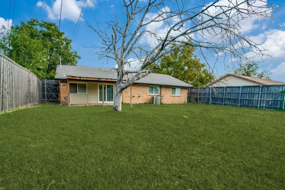 Expansive grassy yard with wood fencing and a brick exterior