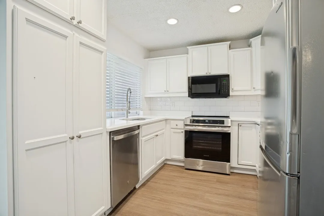 Kitchen featuring white cabinetry, stainless steel appliances, subway tile backsplash, and light wood-finish flooring