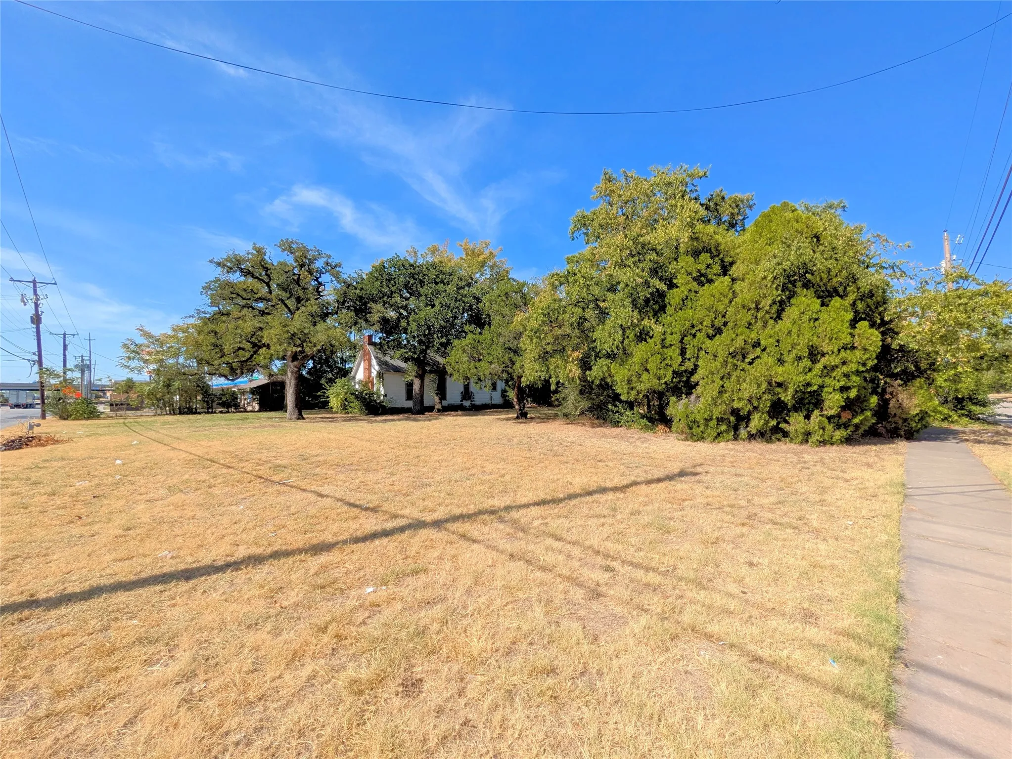 Expansive lot featuring mature trees and a concrete sidewalk