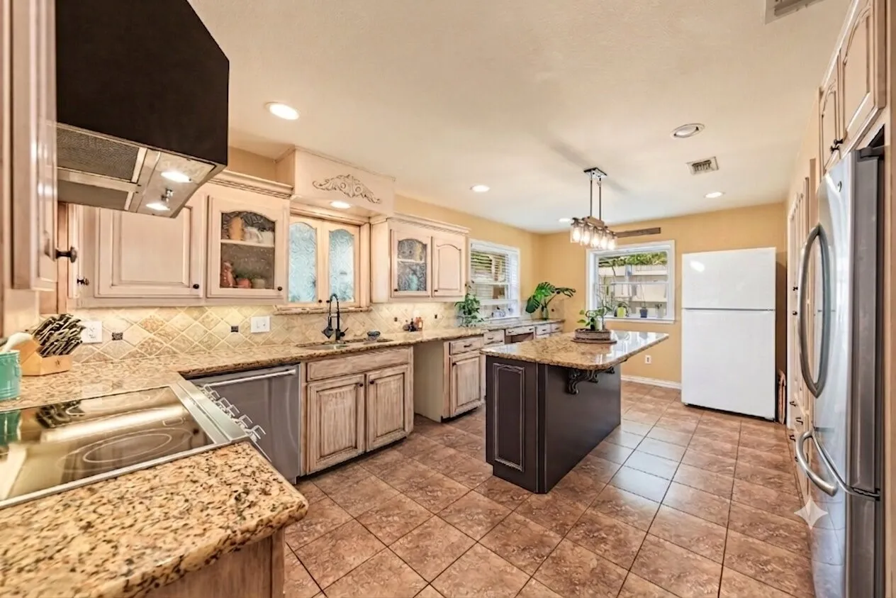 Kitchen featuring an island with granite countertop, tile flooring, recessed lighting, and amble cabinet space