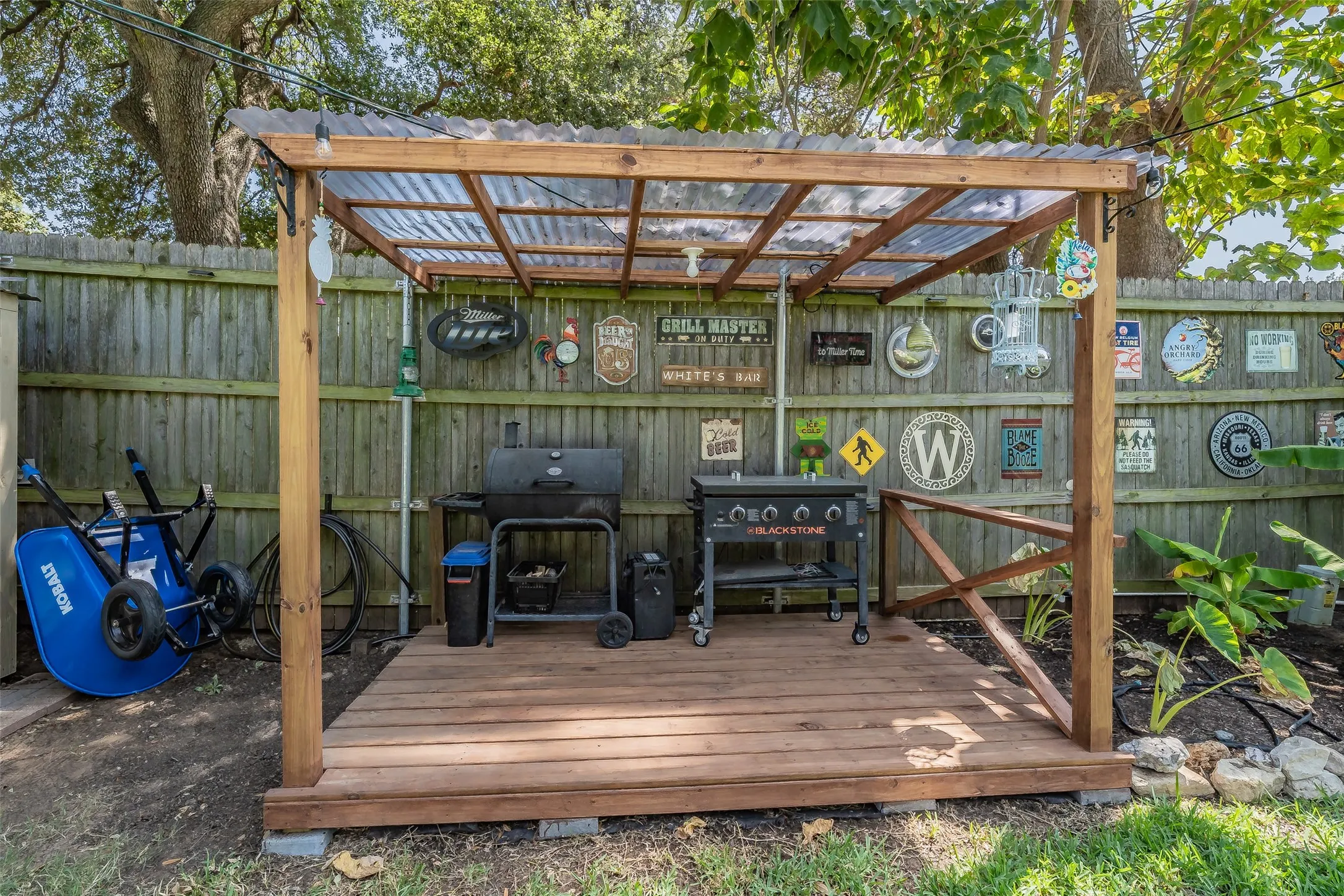 Wood-plank outdoor deck with a translucent corrugated roof covering for BBQ and enterianing