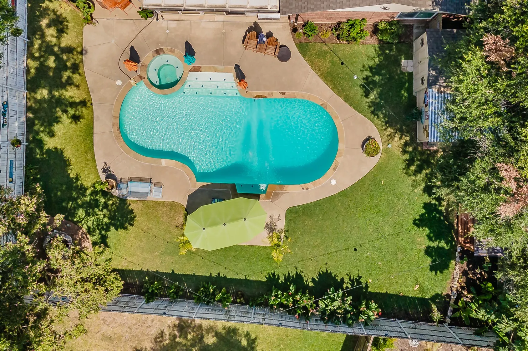 Expansive backyard featuring a freeform swimming pool, integrated spa, and concrete pool deck