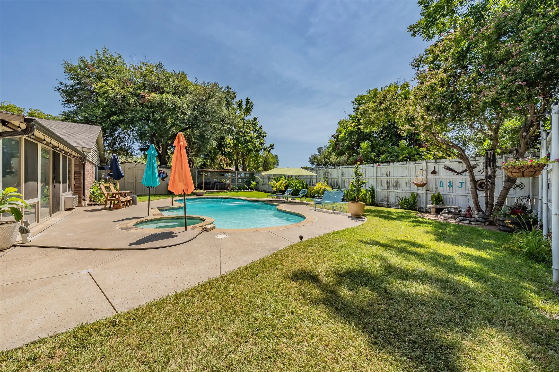 Lush backyard featuring a large swimming pool with an integrated spa, expansive concrete patio, mature trees and beautiful fountain near tree