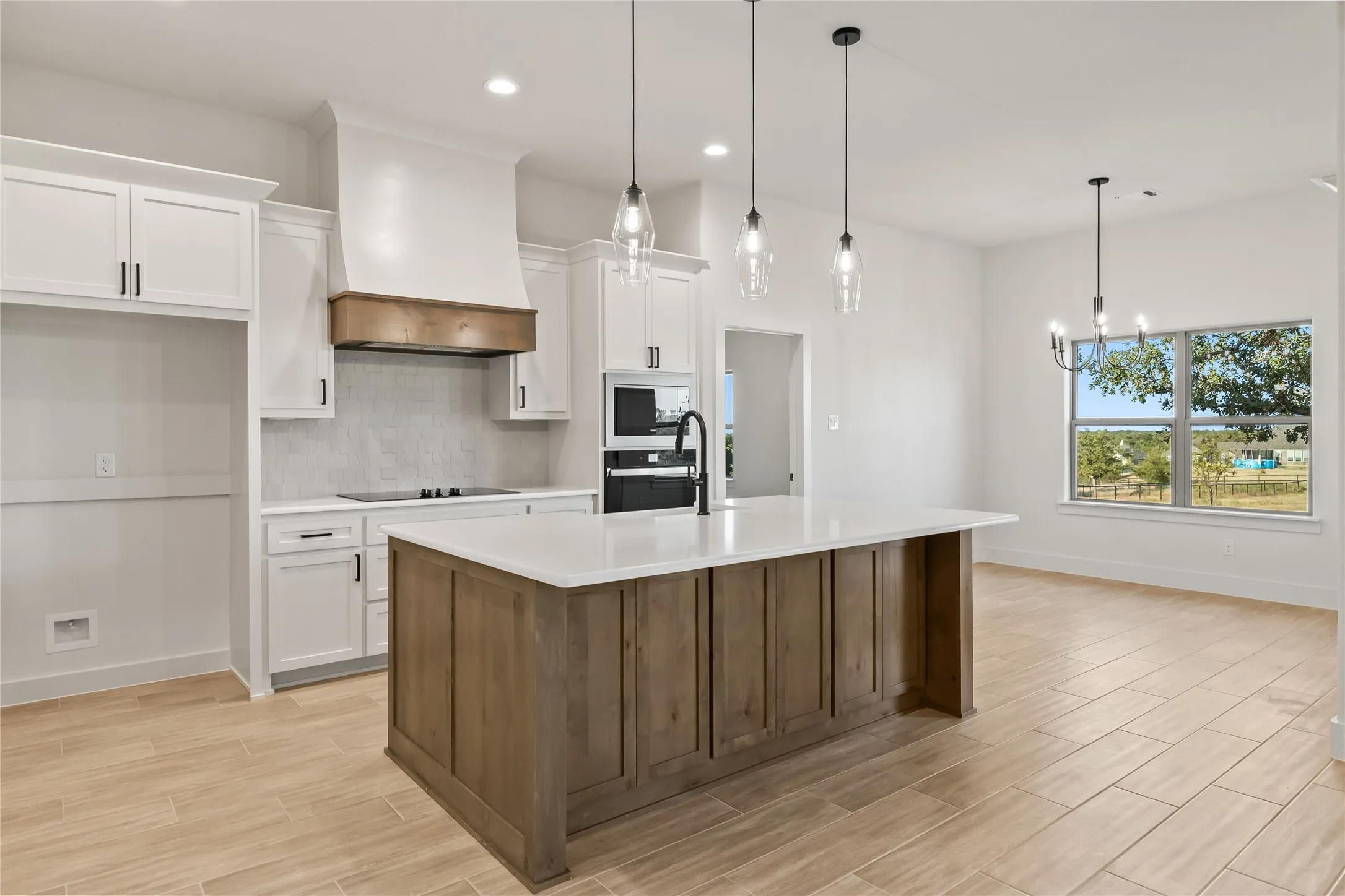 Open-concept kitchen with a large island, white cabinetry, integrated appliances, and wood-finish flooring
