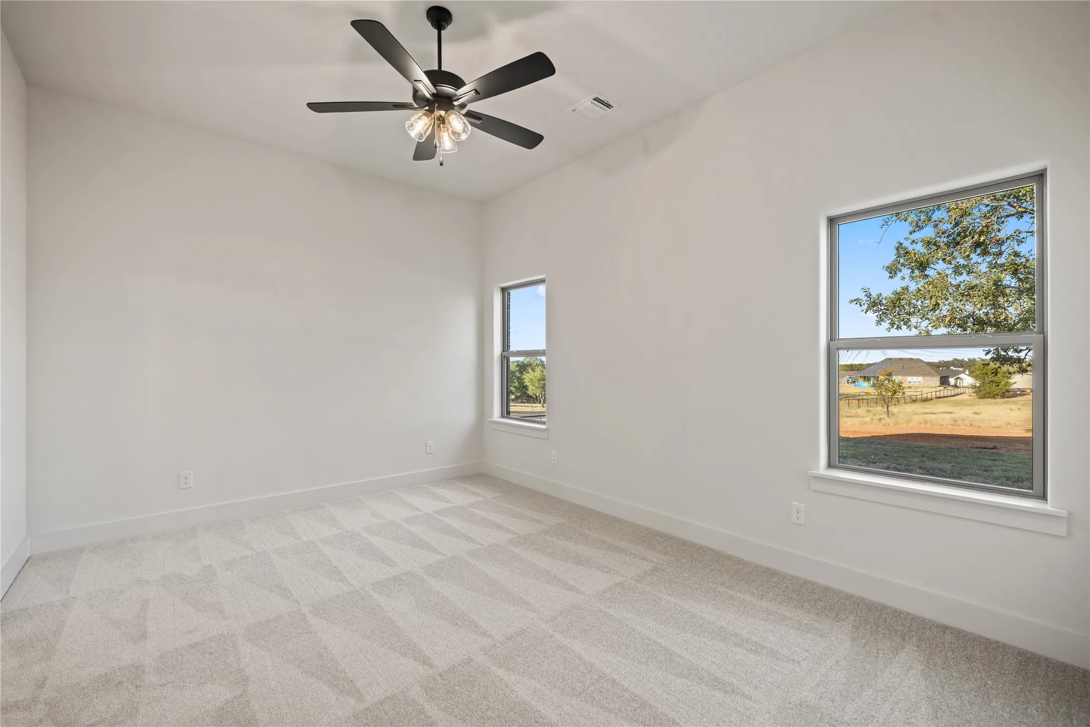 Vaulted ceiling with a ceiling fan, patterned carpet flooring, and multiple windows