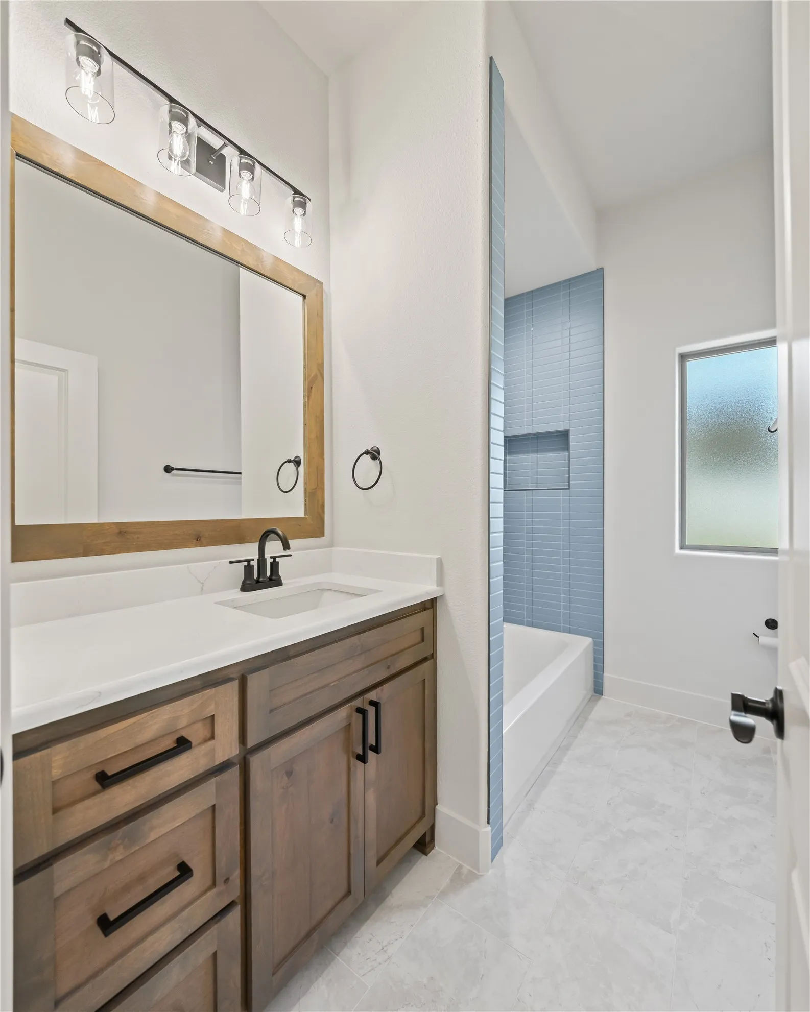 Wood-finish vanity with white countertop, undermount sink, and matte black hardware