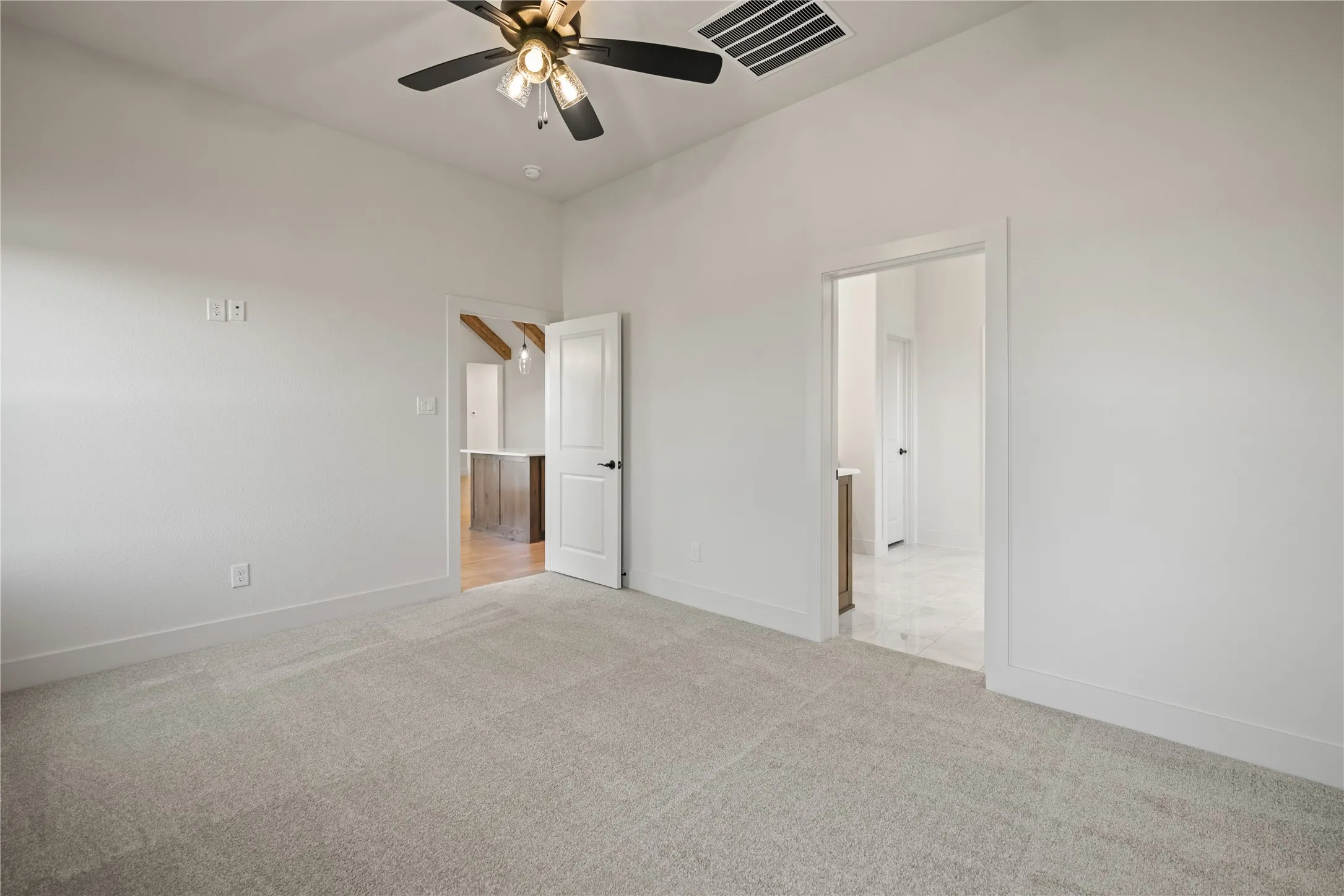 Neutral tone carpeting, vaulted ceiling with a ceiling fan, and white painted walls