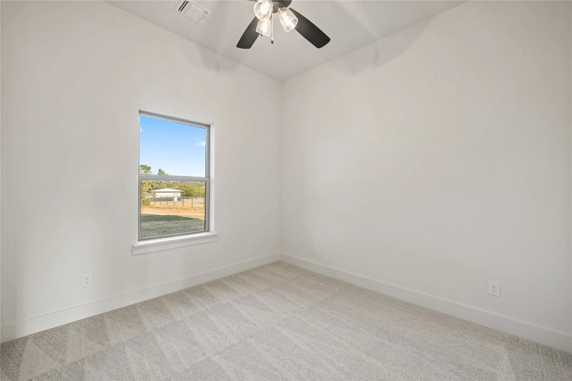 Neutral tone walls with an accent window, light-colored carpet, and a ceiling fan with integrated lighting