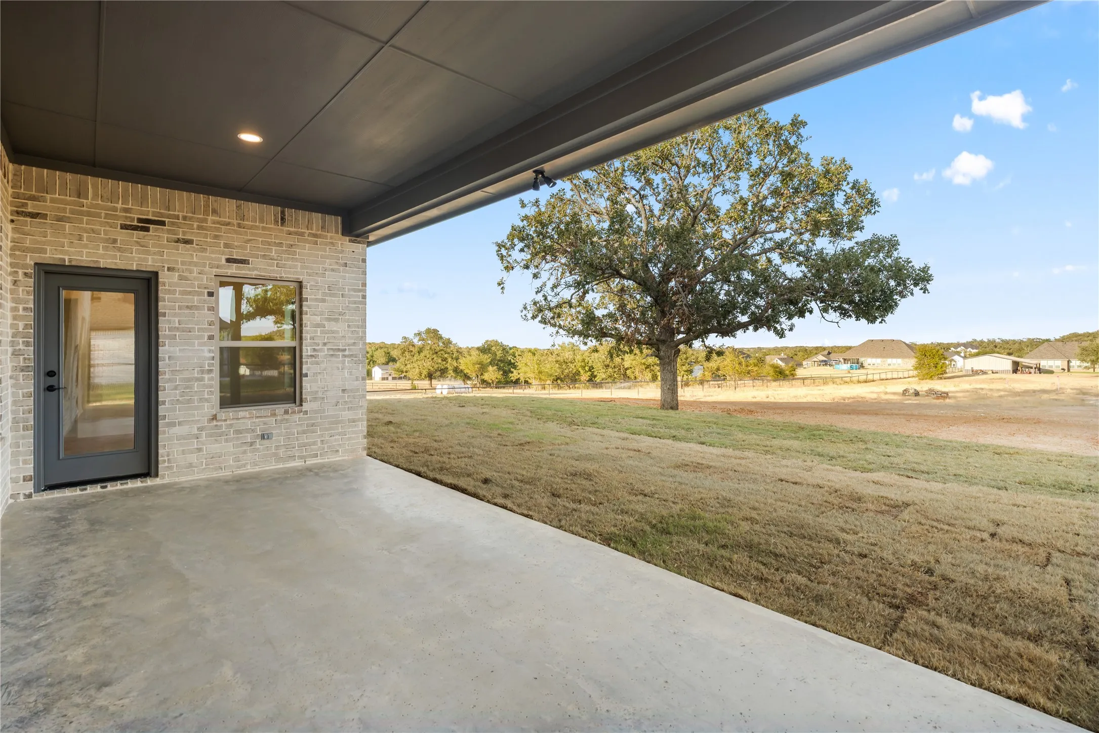 Covered patio with concrete flooring, recessed lighting, brick exterior wall, and glass-paneled door