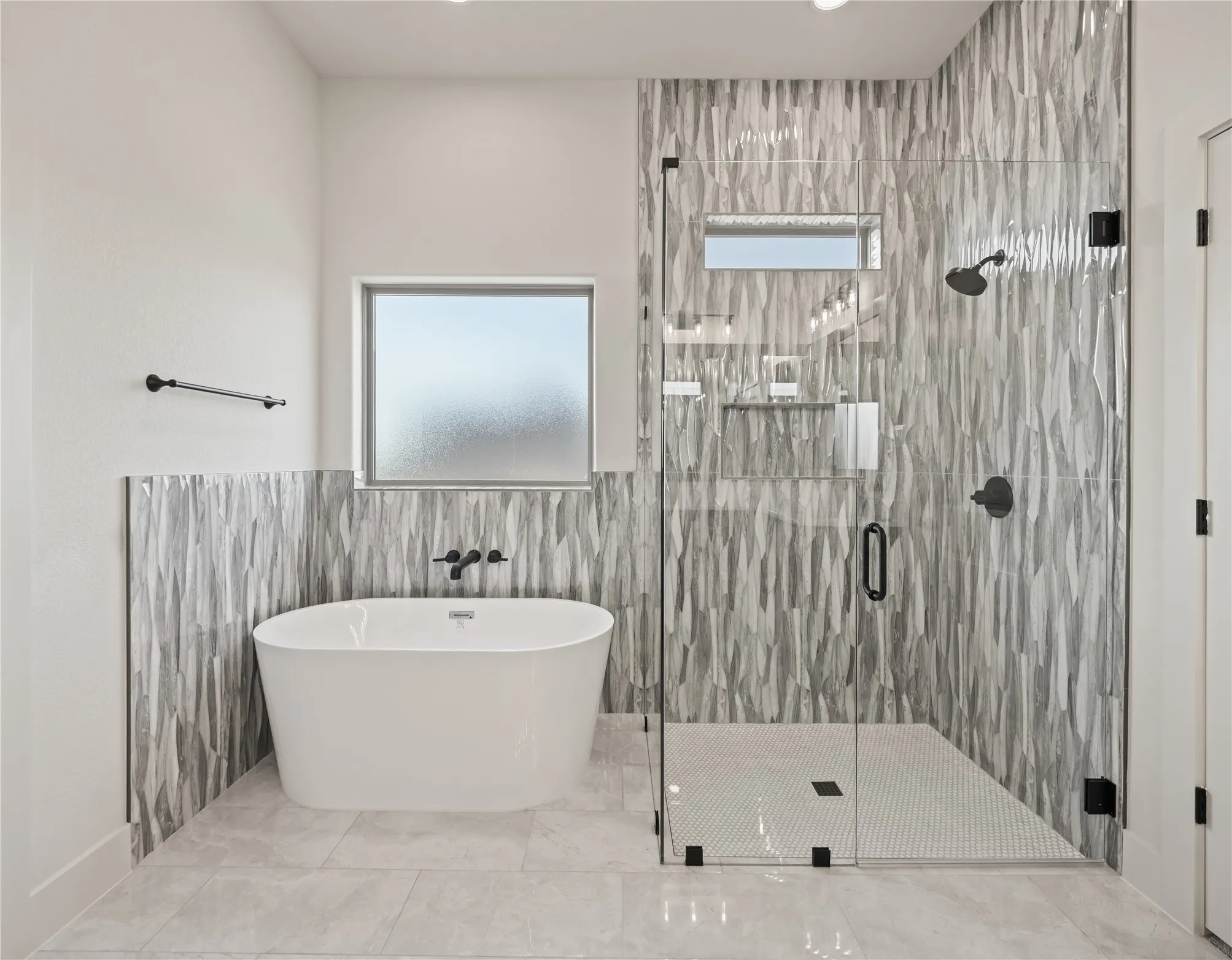 Freestanding soaking tub with wall-mounted matte black faucet, walk-in shower with glass enclosure, textured tile shower surround, and tile flooring