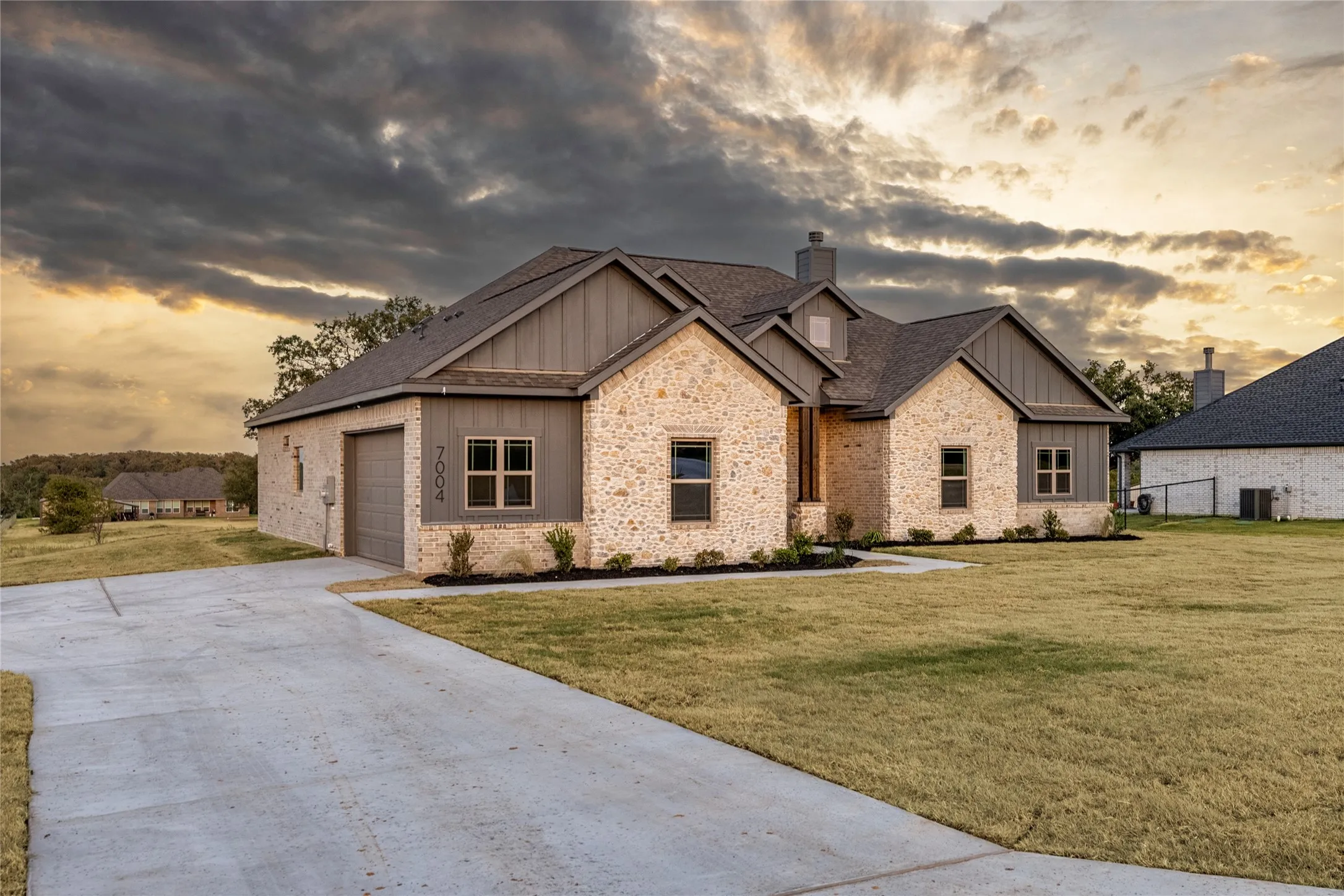 Stone and vertical siding exterior with a dark shingled roof