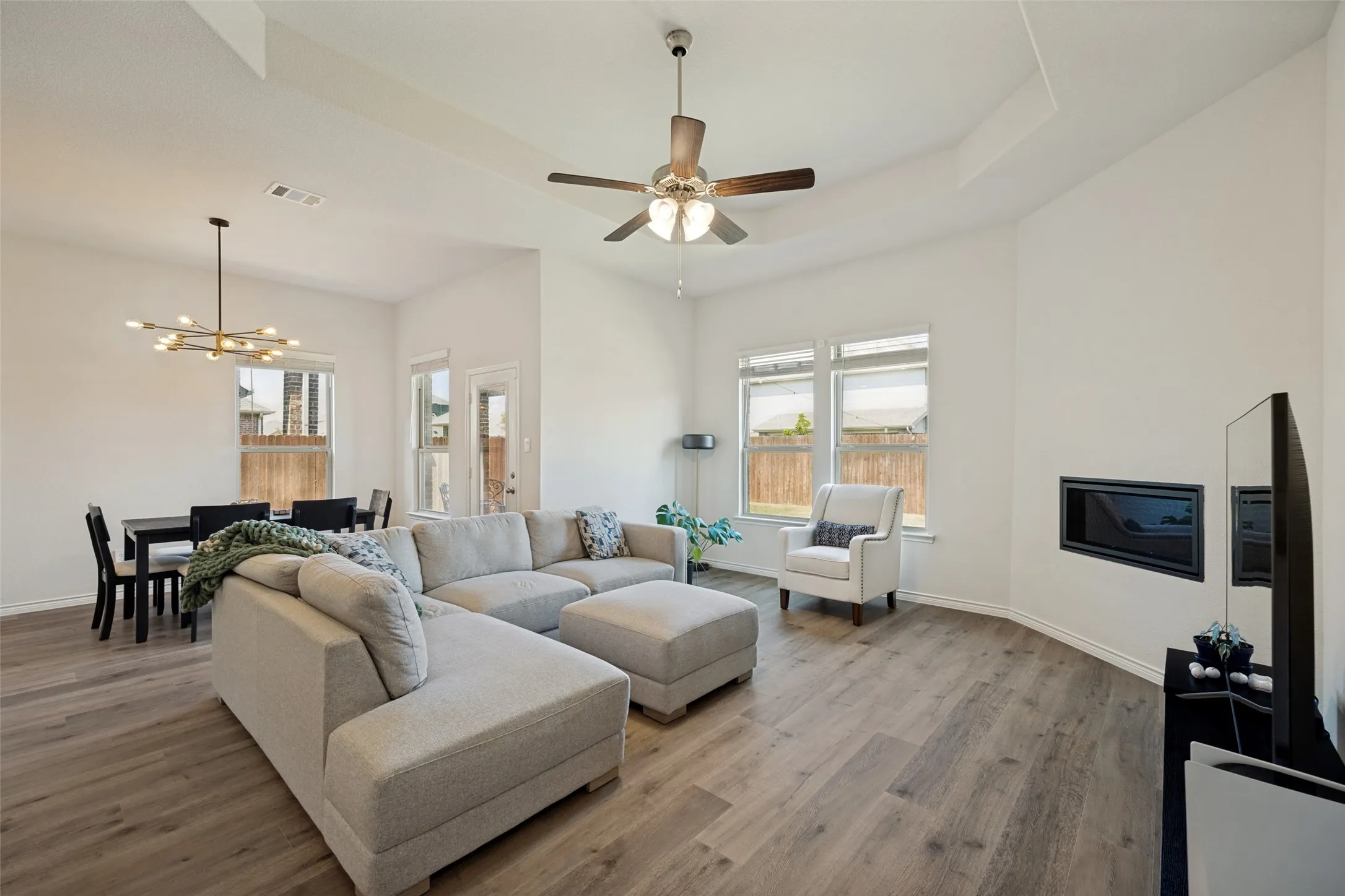 Spacious living area featuring wood-finish flooring, a contemporary ceiling fan, and an integrated wall-mounted fireplace