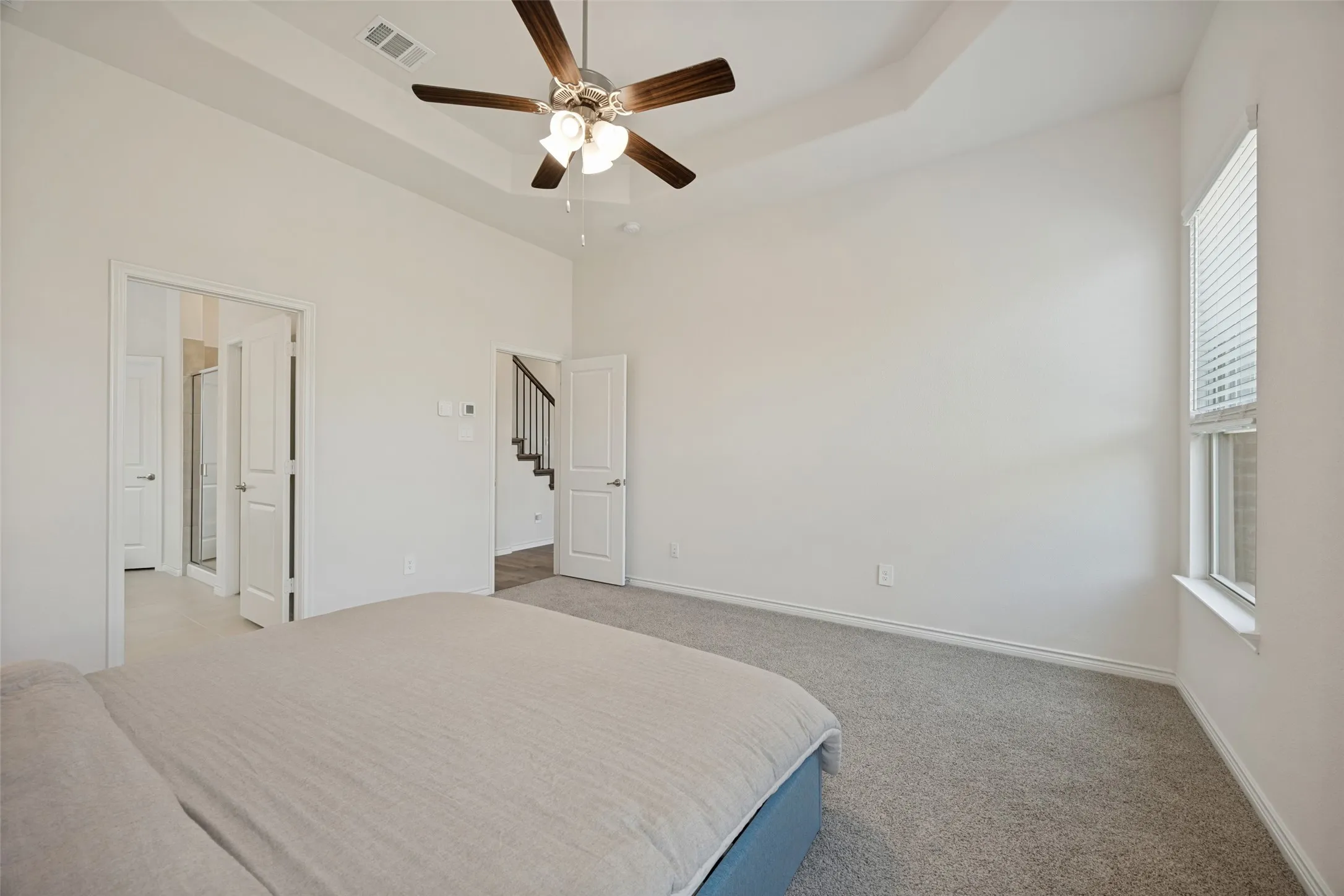 Tray ceiling with recessed lighting, ceiling fan with light fixture, carpeted flooring, and window with blinds