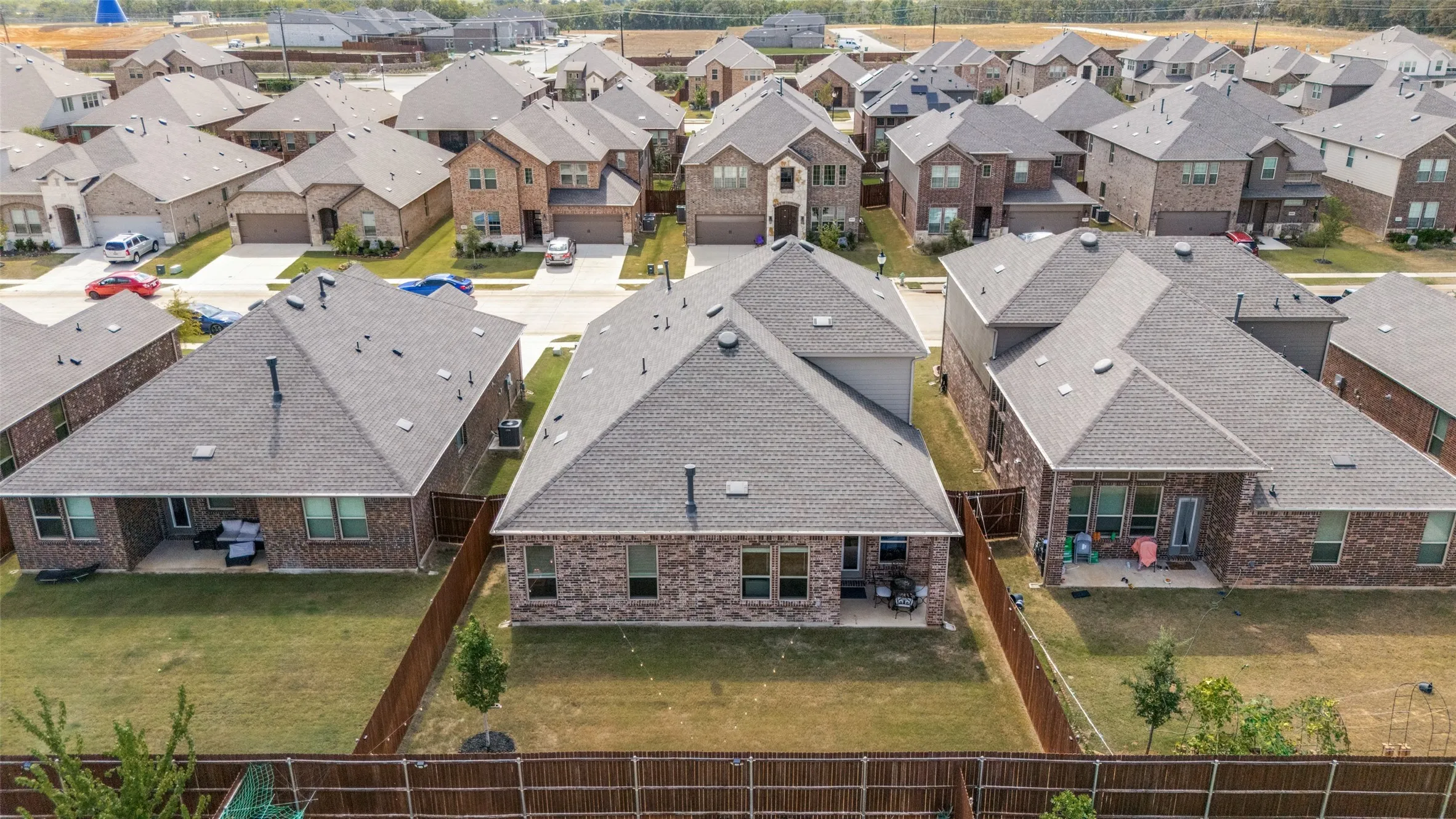 Rear exterior with a covered patio, brick facade, and fenced yard