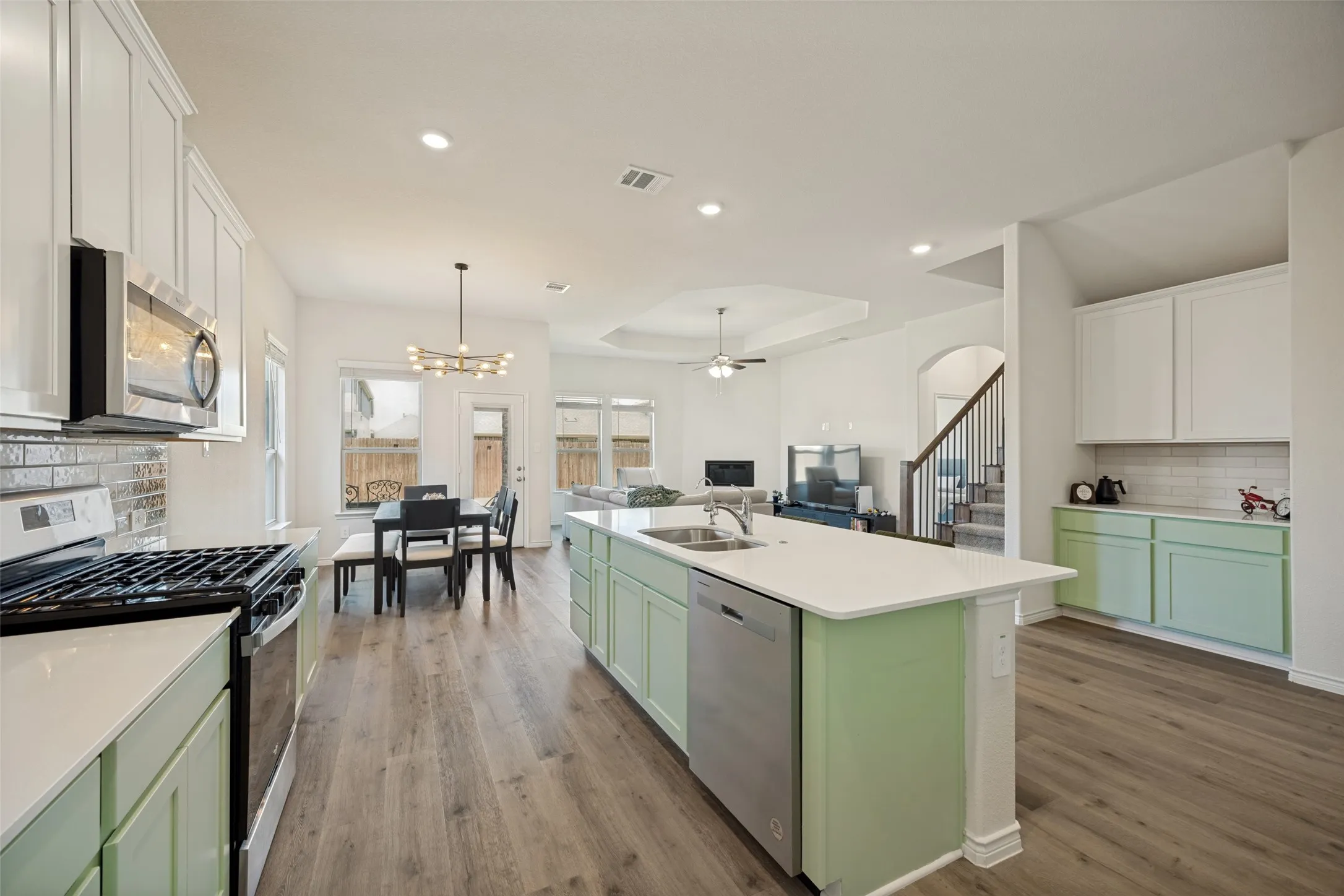 Spacious kitchen featuring an expansive island, stainless steel appliances, white countertops, and wood-finish flooring
