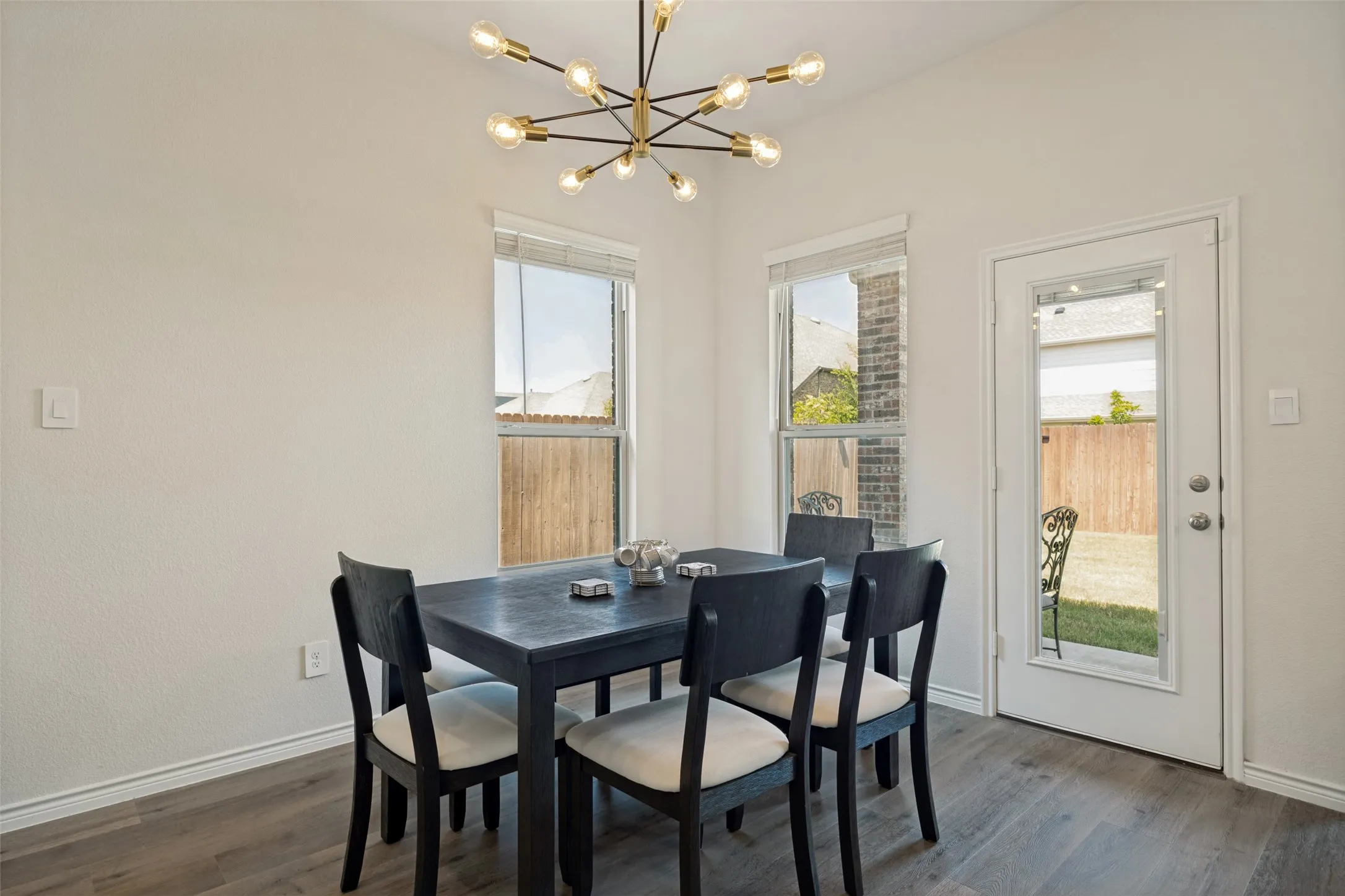 Vaulted ceiling with a modern sputnik chandelier, two windows, and a glass-paneled door