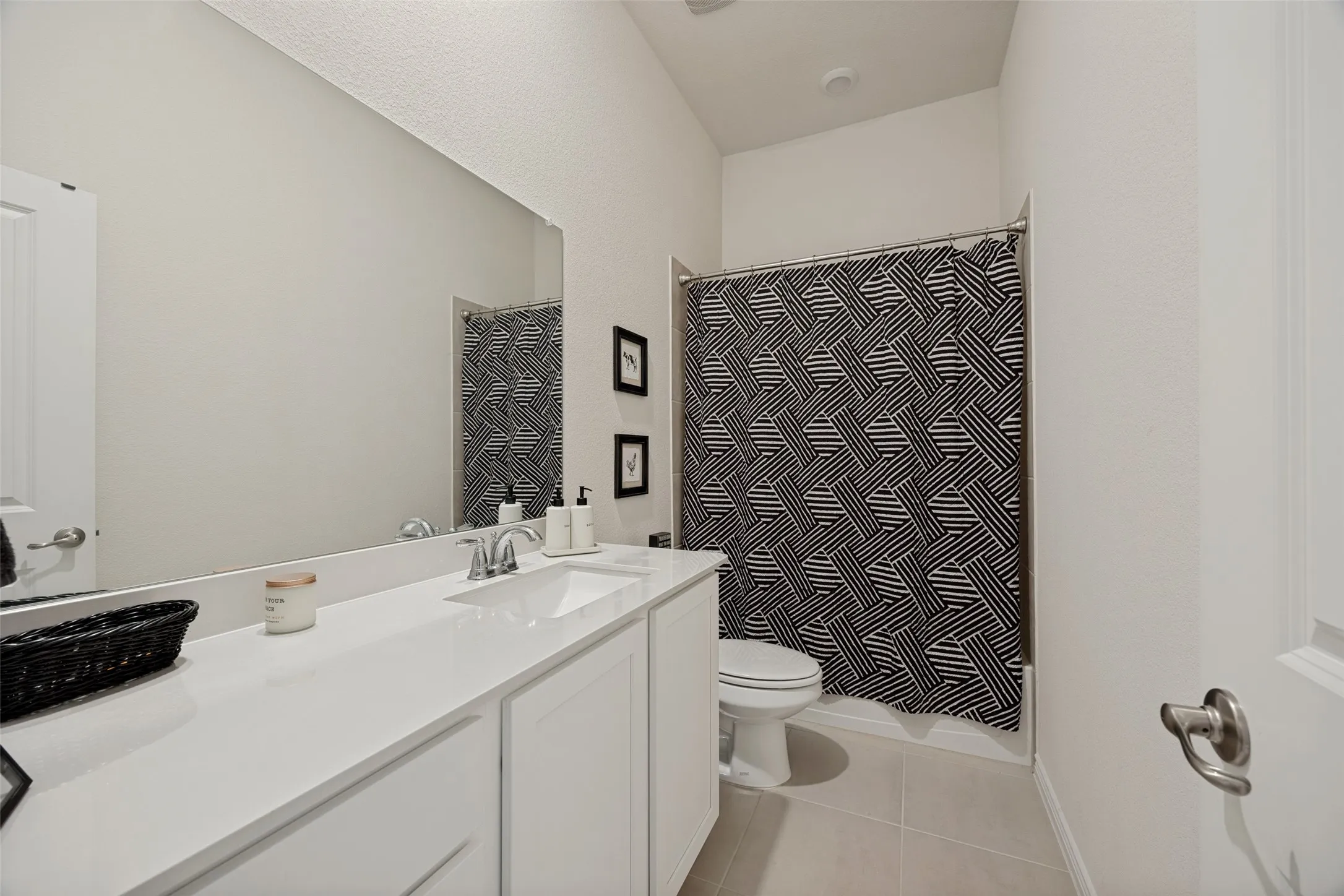 Vanity with a single basin sink, white cabinetry, and an expansive wall mirror