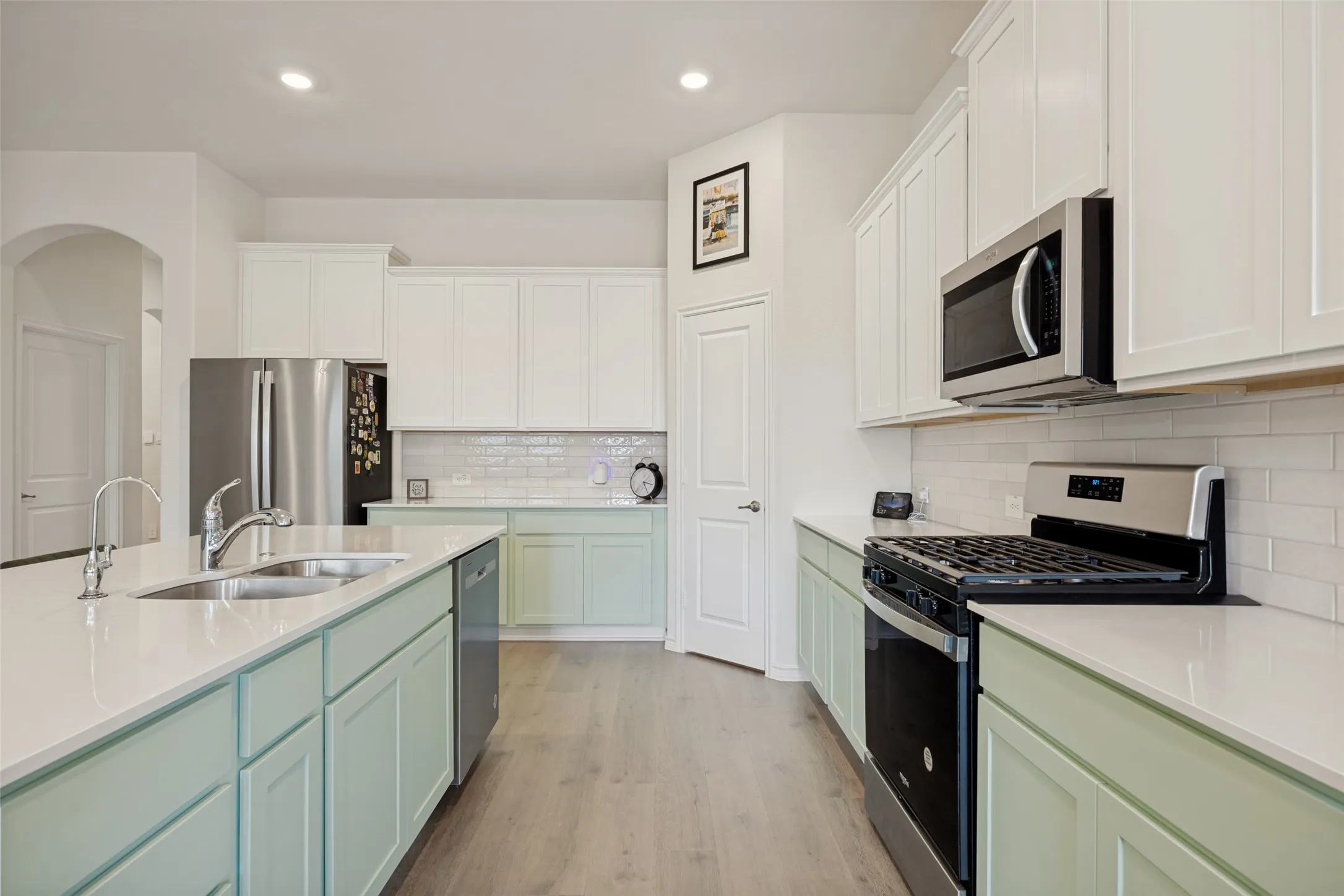Kitchen featuring light-toned upper cabinetry, green lower cabinetry, wood-finish flooring, white countertops, and subway tile backsplash