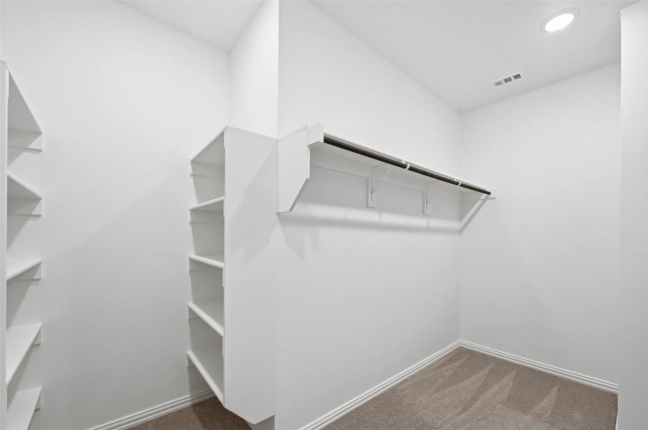 Built-in shelving, hanging rod, recessed lighting, and carpeted flooring