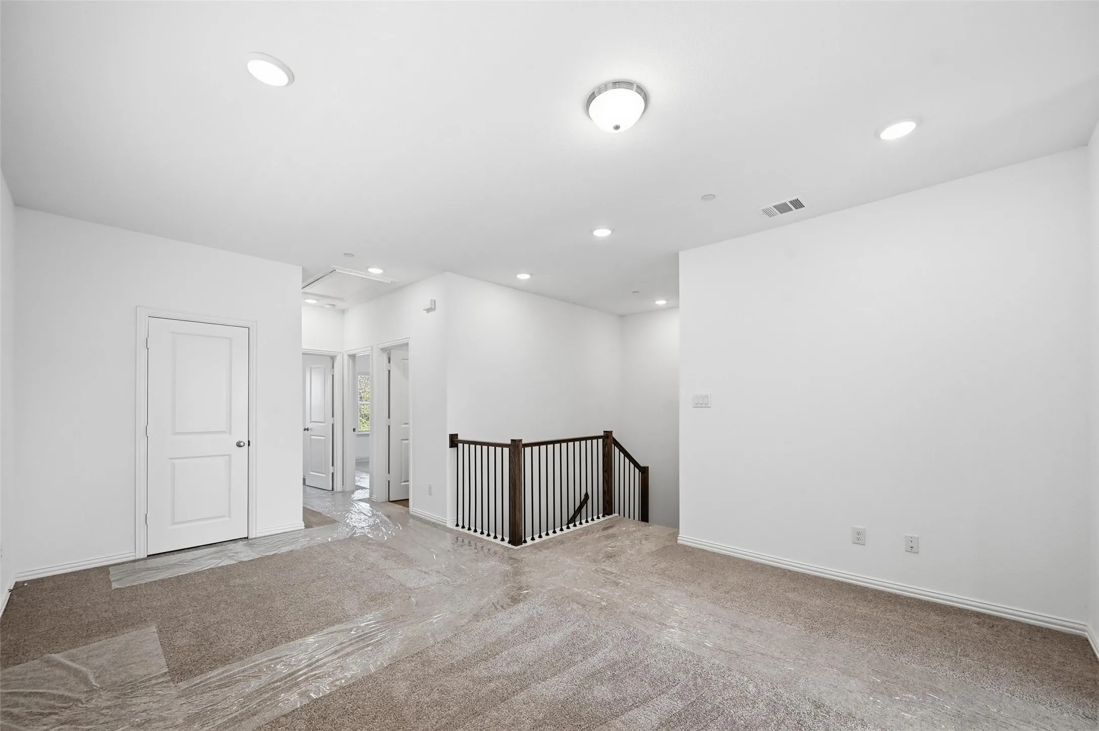 Plush carpet flooring, recessed ceiling lighting, two-panel interior doors, and a wood and metal baluster staircase