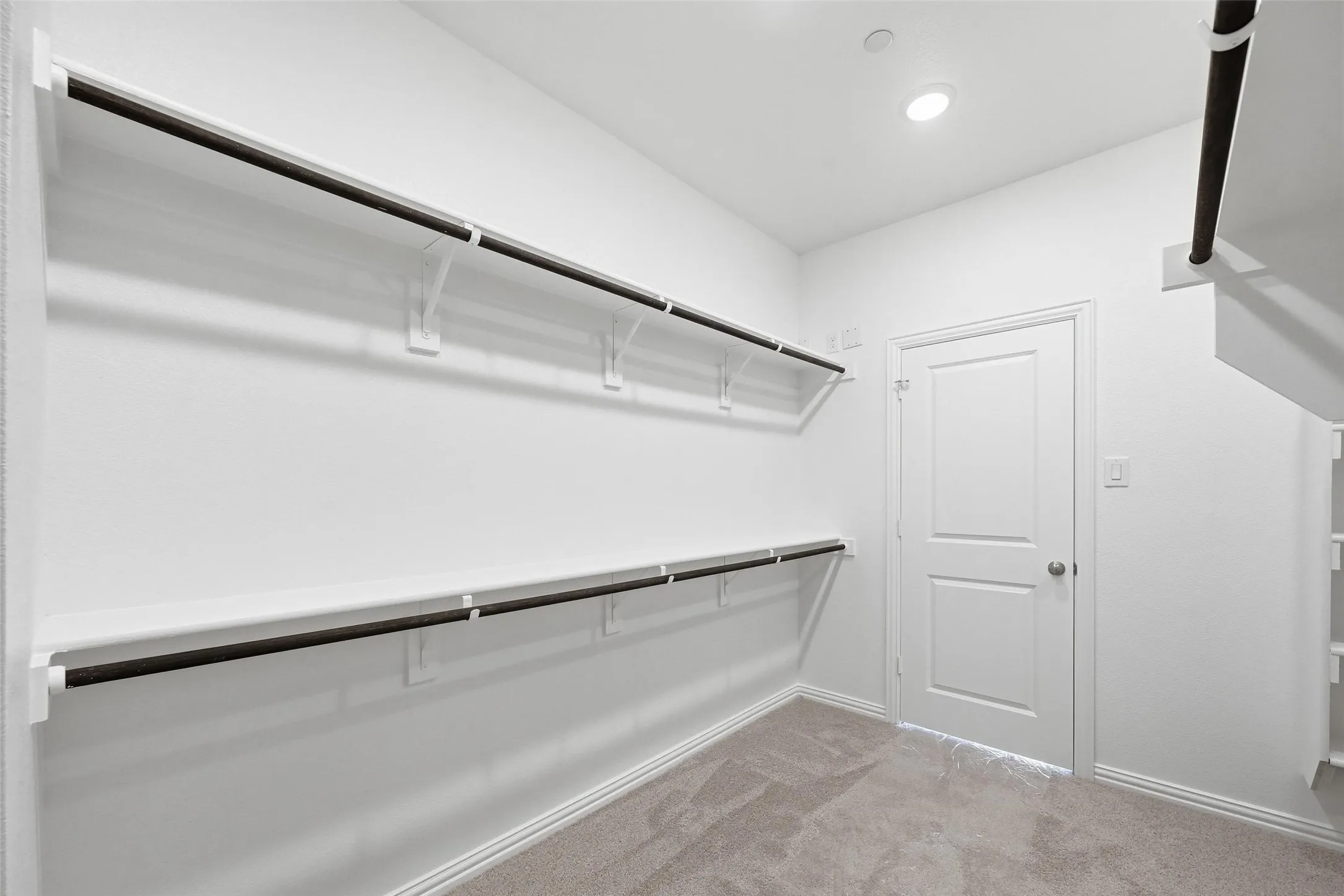 Built-in shelving with hanging rods, recessed ceiling lighting, and neutral carpeting