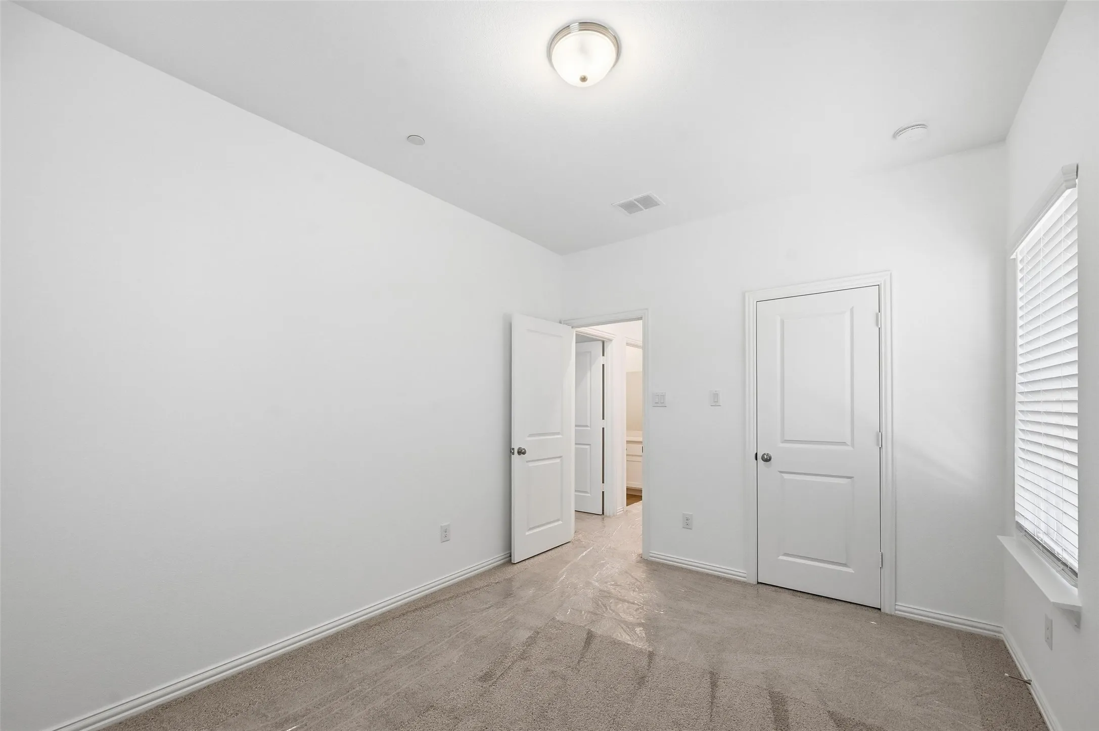 Recessed lighting, flush mount ceiling fixture, window with blinds, panel doors, and carpet flooring