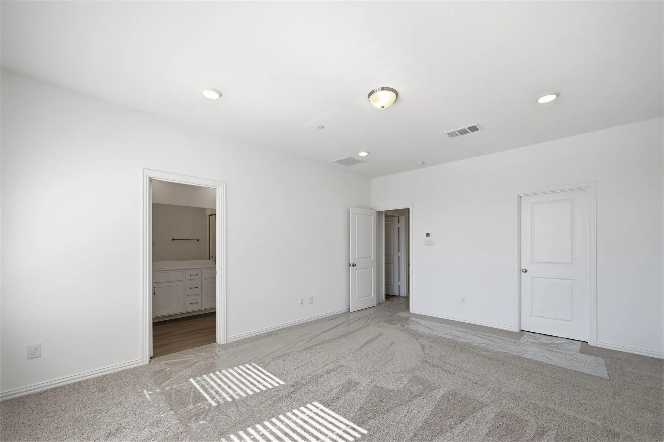 Spacious room with light gray carpeting, recessed lighting, and a surface-mounted ceiling light fixture