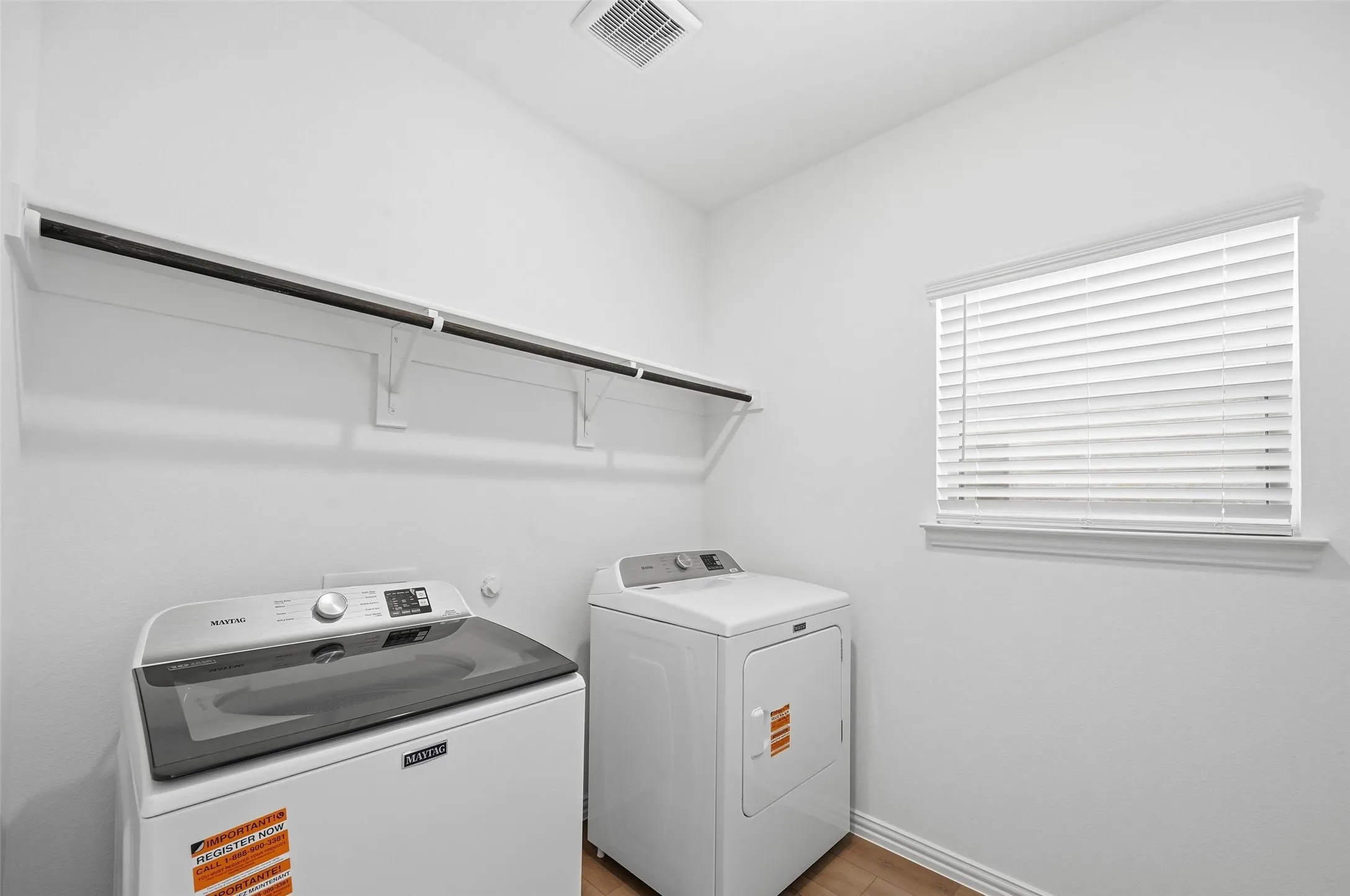 Laundry area featuring built-in shelving, a clothes hanging rod, a window with blinds, and wood-finish flooring