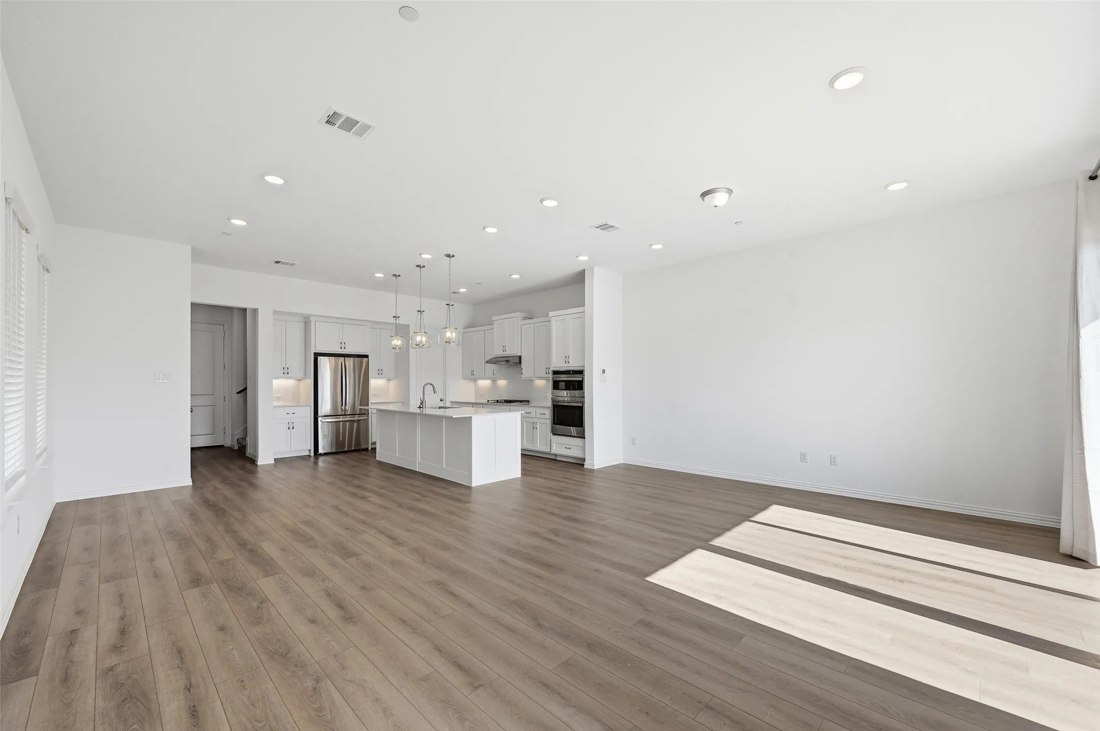 Open-concept living area with wood-finish flooring, recessed lighting, and white walls