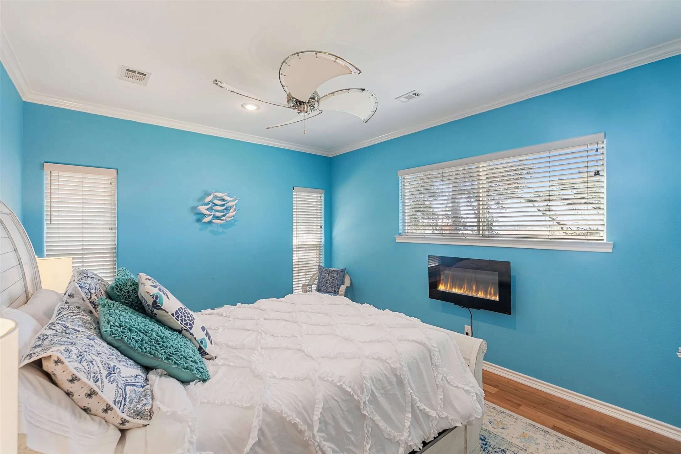 Room featuring a wall-mounted electric fireplace, bamboo flooring, and crown molding