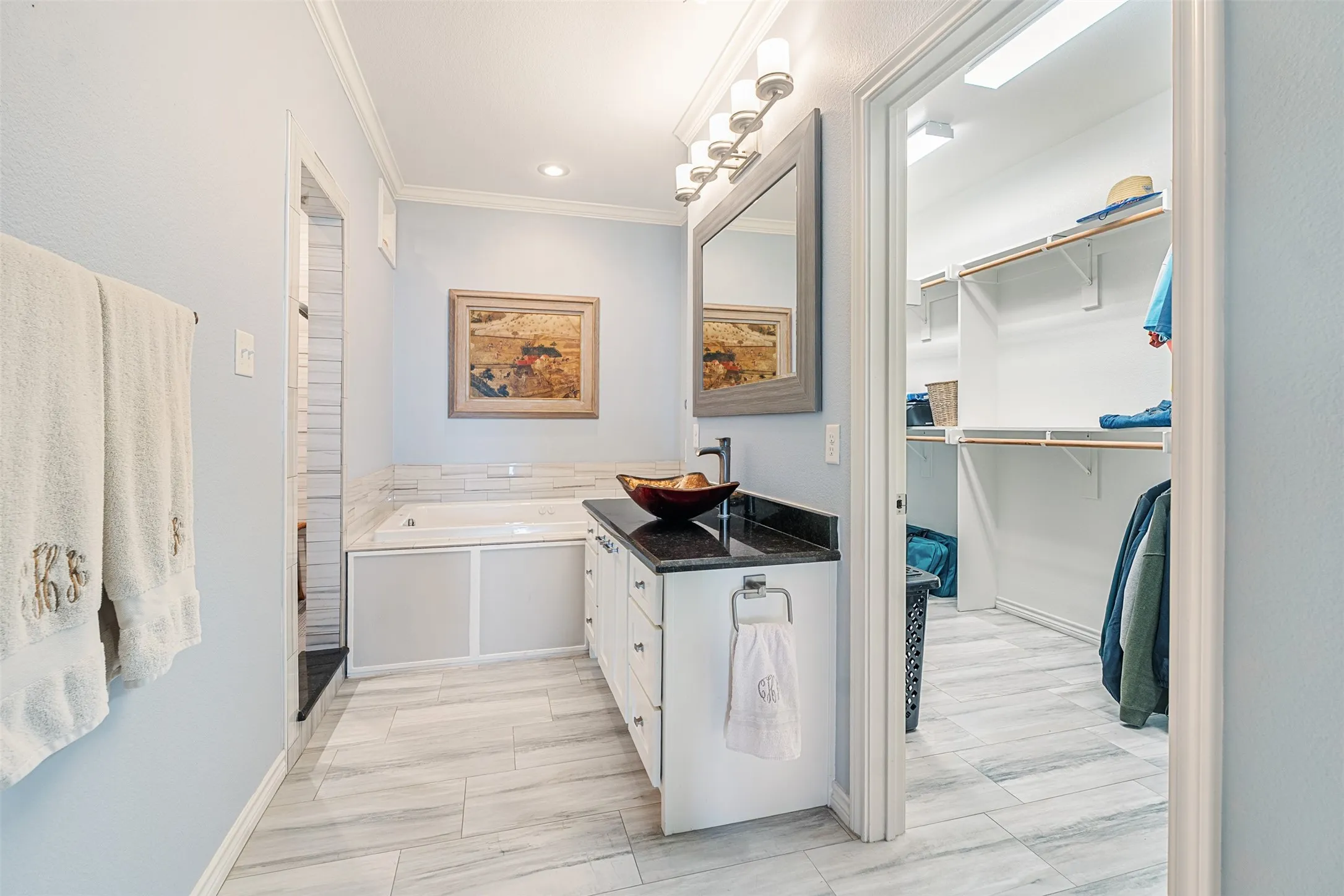 White cabinetry with black countertop, vessel sink, and wall-mounted​​‌​​​​‌​​‌‌​‌‌​​​‌‌​‌​‌​‌​​​‌​​ mirror