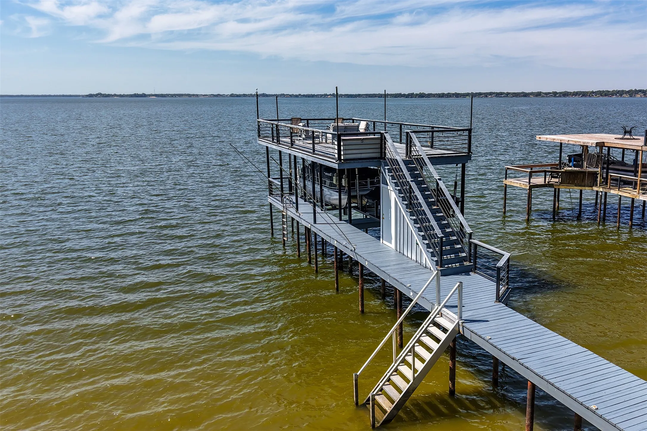 Two-story boat dock with a top-level deck, metal railings, and a multi-level stairway