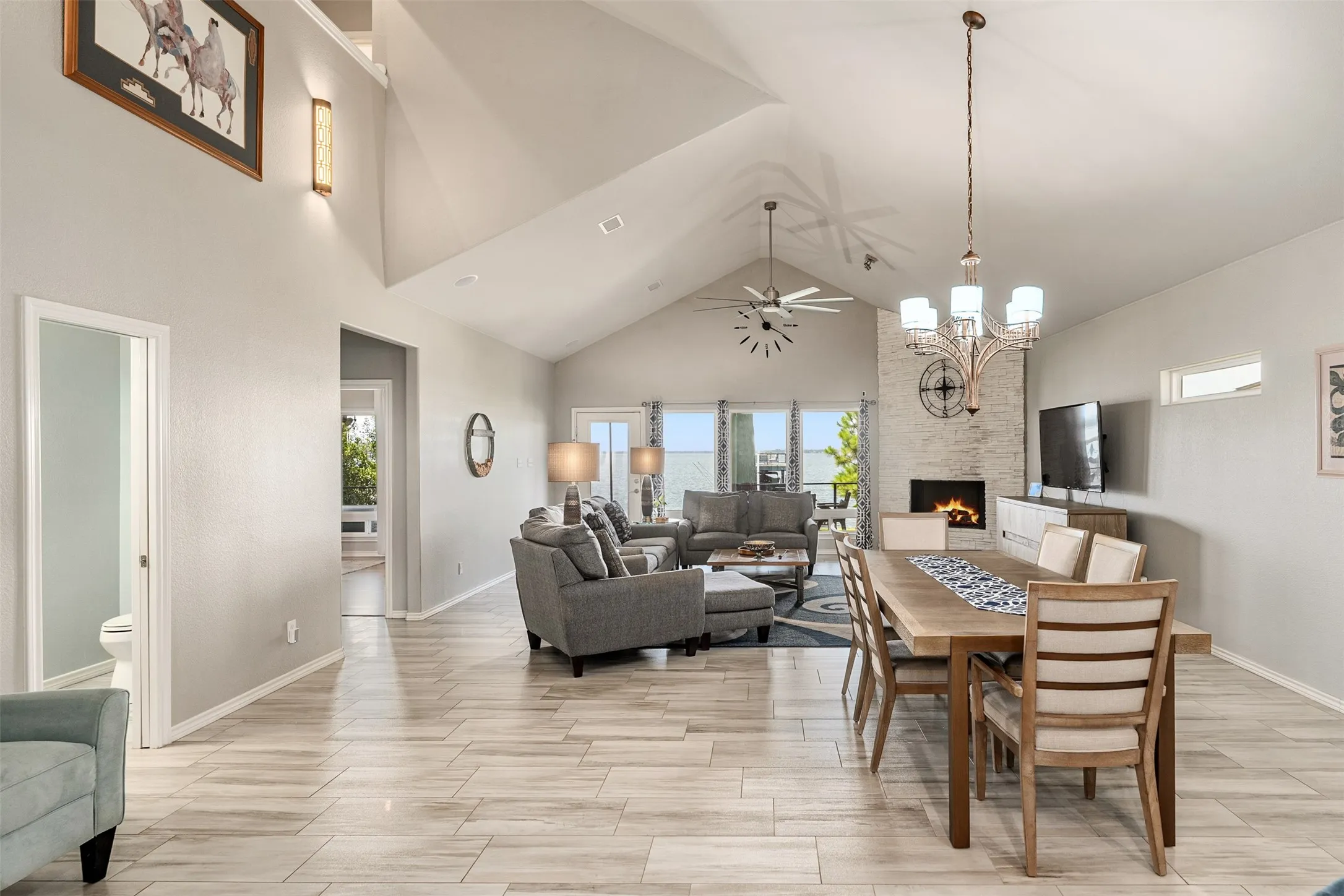 Vaulted ceiling recessed lighting, tile flooring, stone-clad fireplace, and chandelier lighting