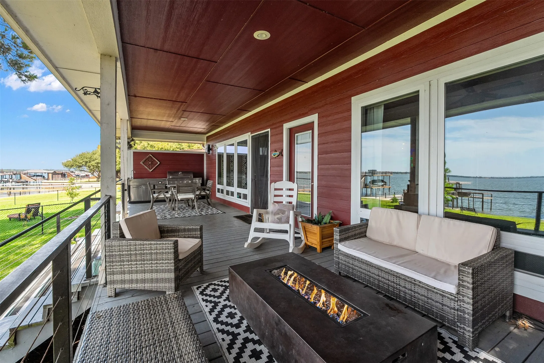 Expansive covered porch with a dark wood-finish ceiling and a fire table