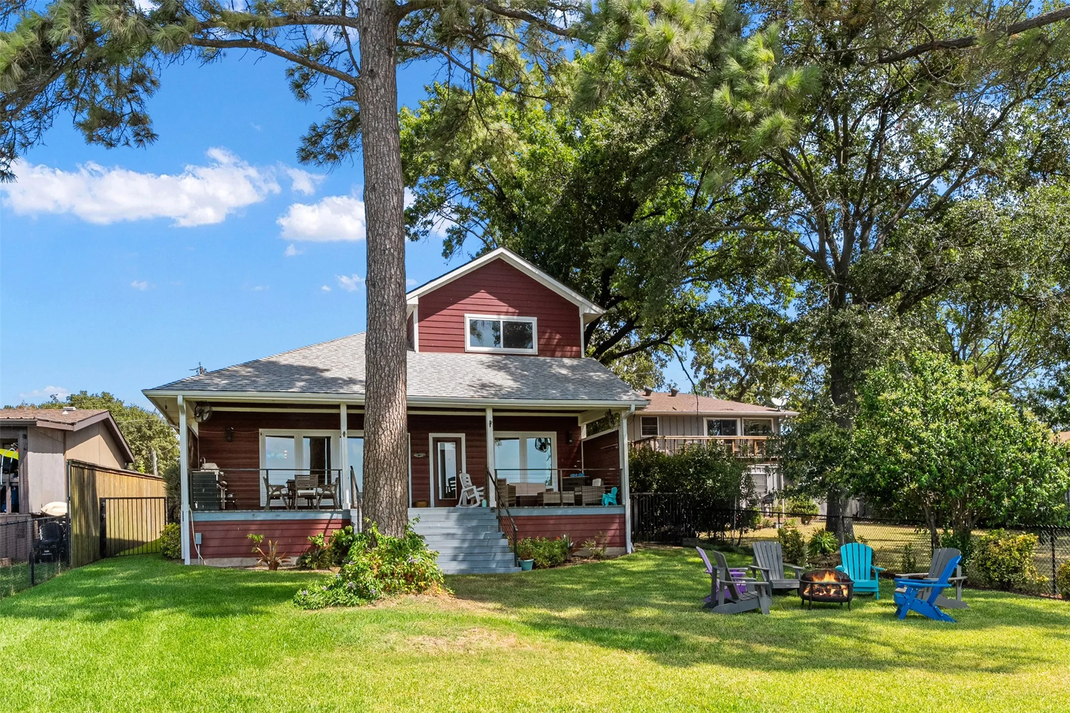 Red siding exterior with a partial covered porch, multiple windows, and exterior stairs
