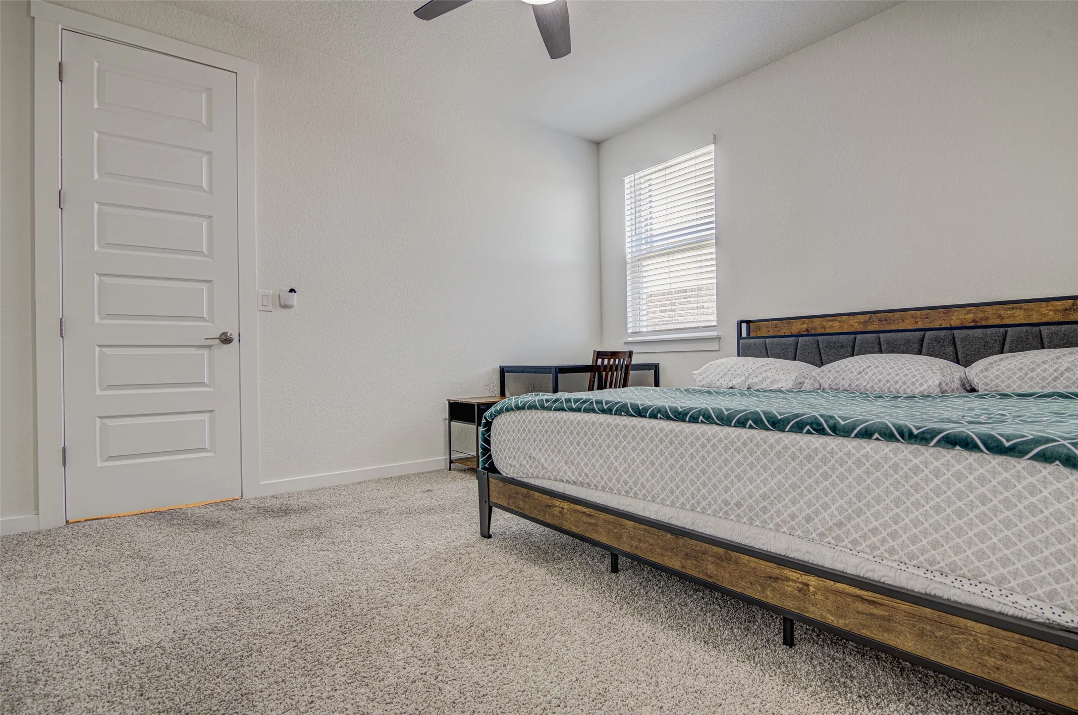 Plush carpeting, a modern five-panel interior door, and a ceiling fan with integrated lighting
