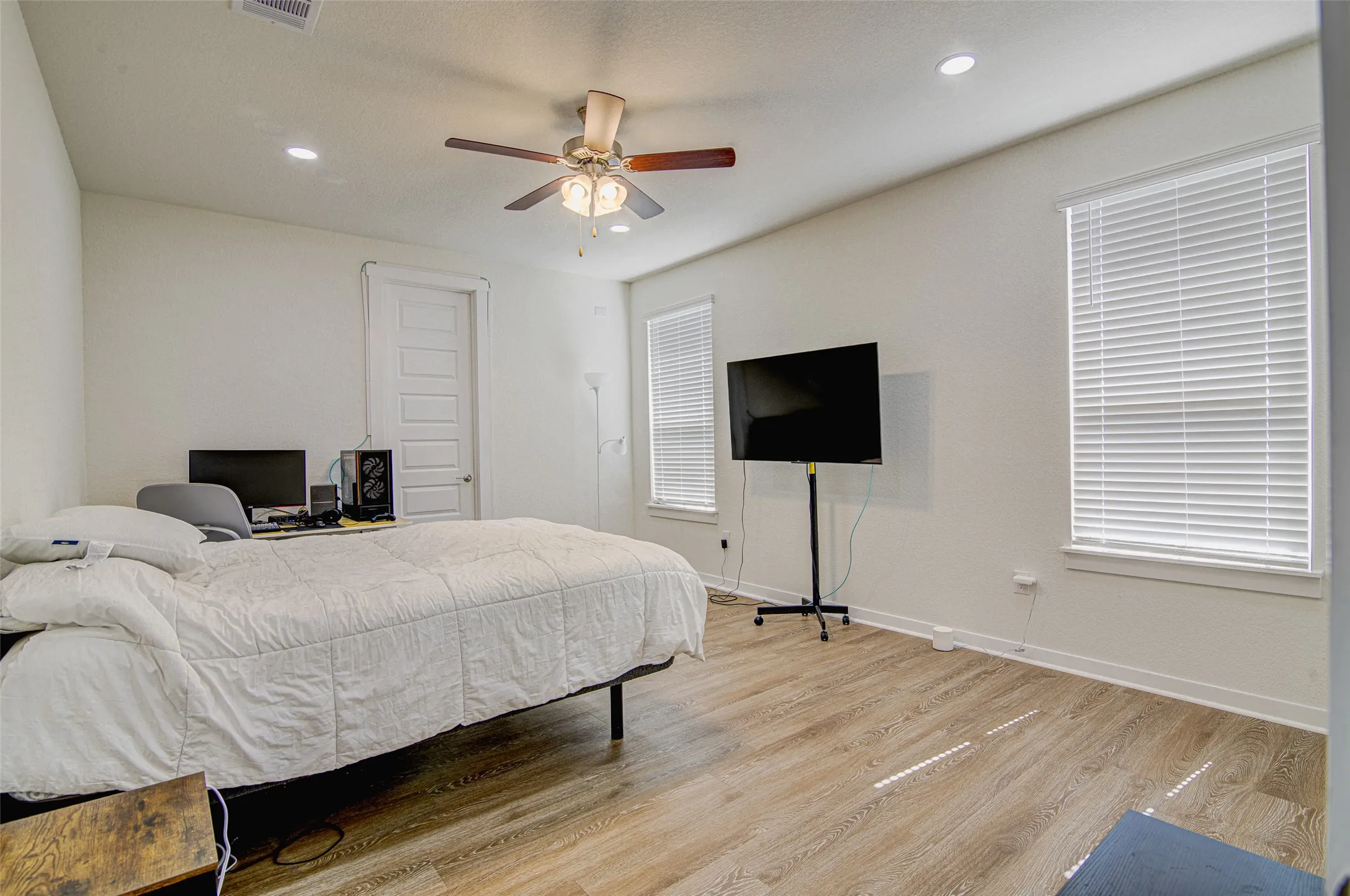 Recessed lighting, wood-finish flooring, ceiling fan with integrated lighting, and two windows with blinds