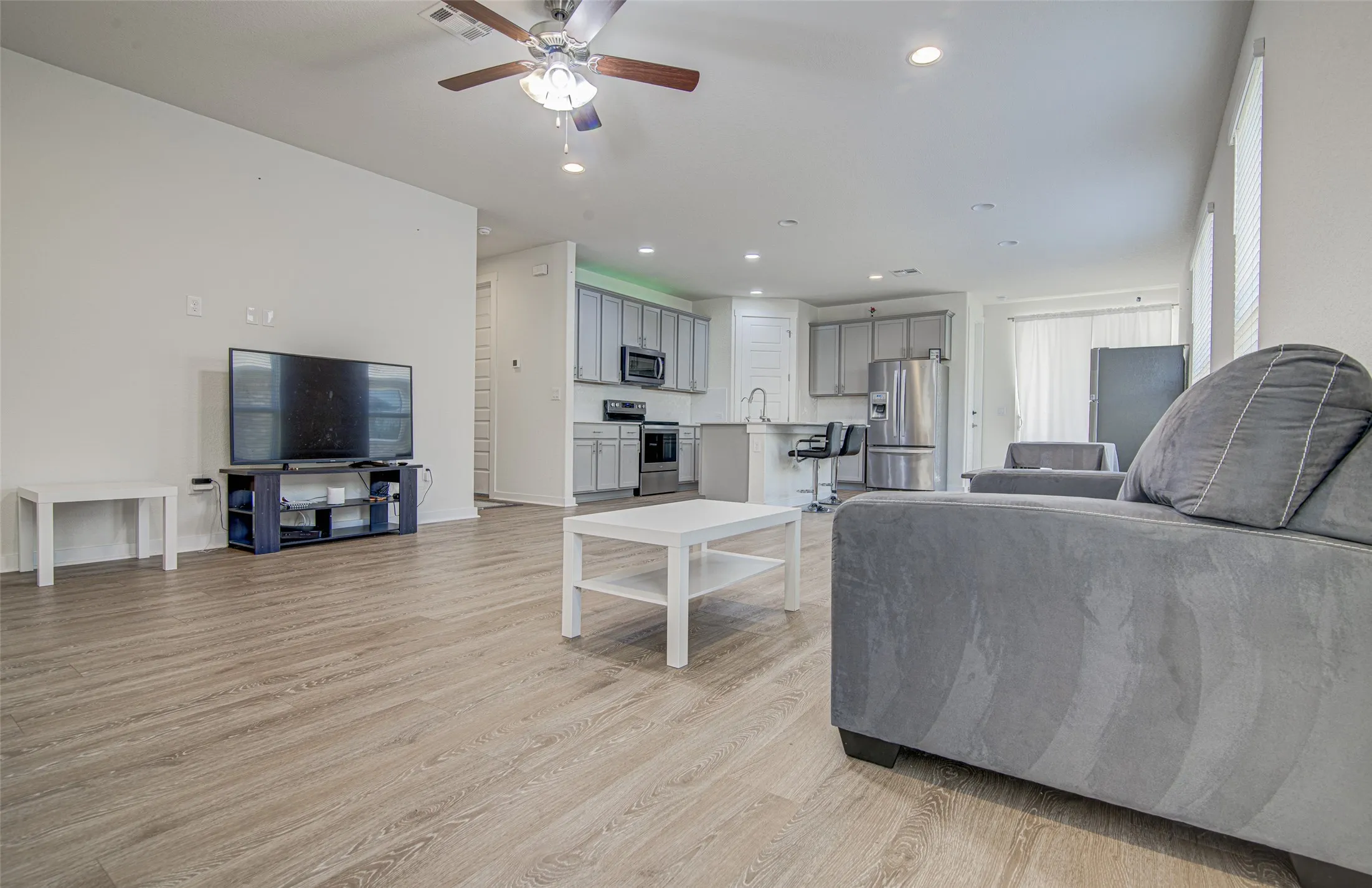 Open-concept living area featuring wood-finish flooring, recessed lighting, and a ceiling fan