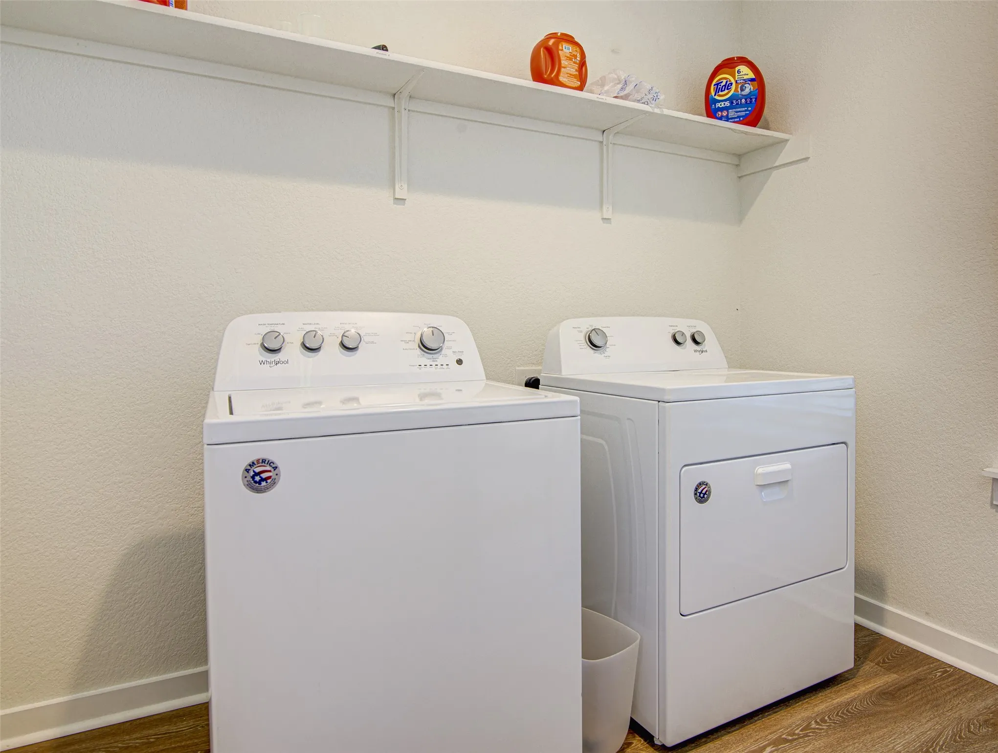 Utility area featuring a washer and dryer, wood-finish flooring, and wall-mounted shelving