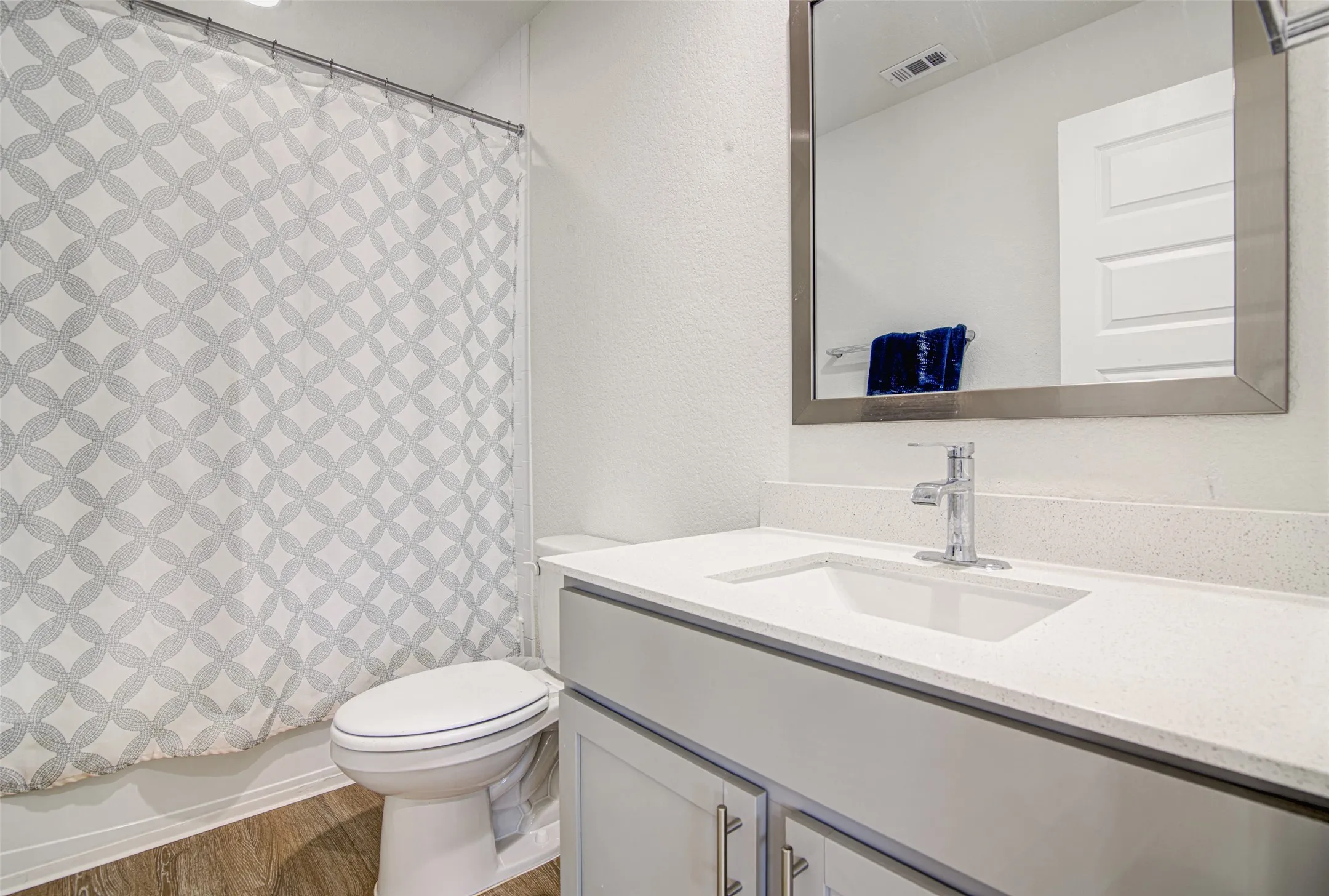 White vanity with integrated sink, chrome faucet, and rectangular mirror