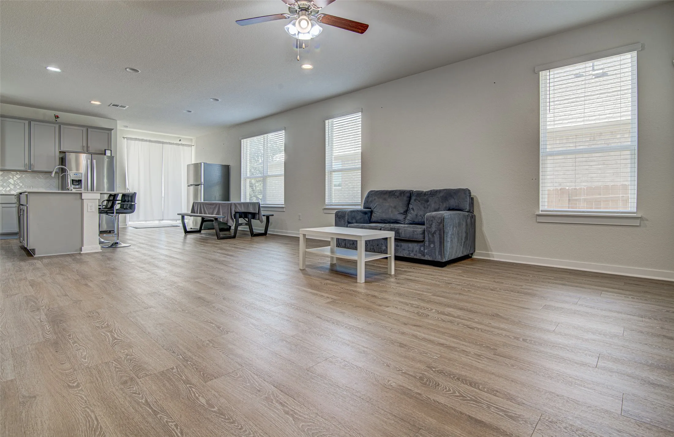 Open-concept living area featuring wood-finish flooring, recessed lighting, and a ceiling fan