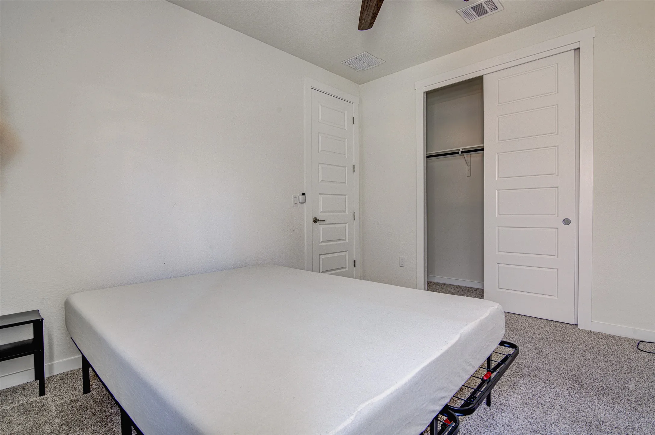Carpeted flooring with white walls and a ceiling fan